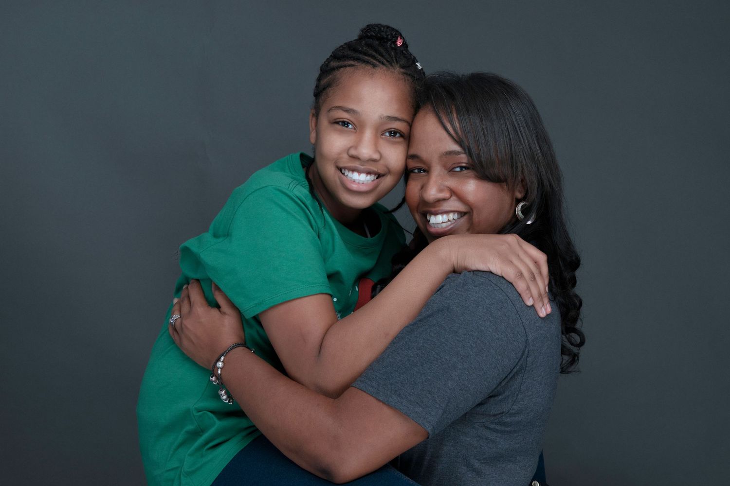 Heartwarming embrace between mother and daughter against dark background.