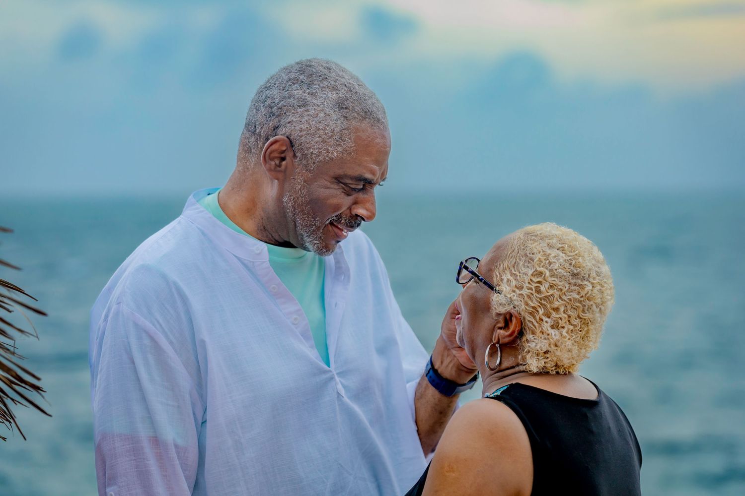 Loving couple shares a tender moment together by the ocean at sunset.