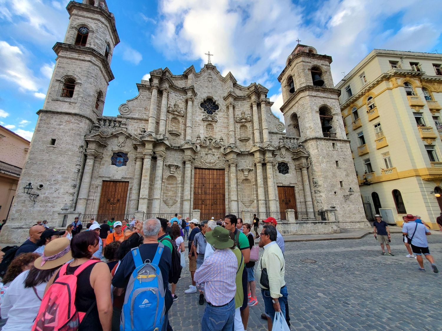 Tourists gather in front of the ornate Havana Cathedral with its baroque facade and twin bell towers in Cuba.