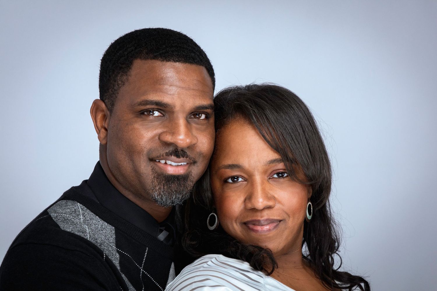 Professional studio portrait of couple in formal attire against grey background.