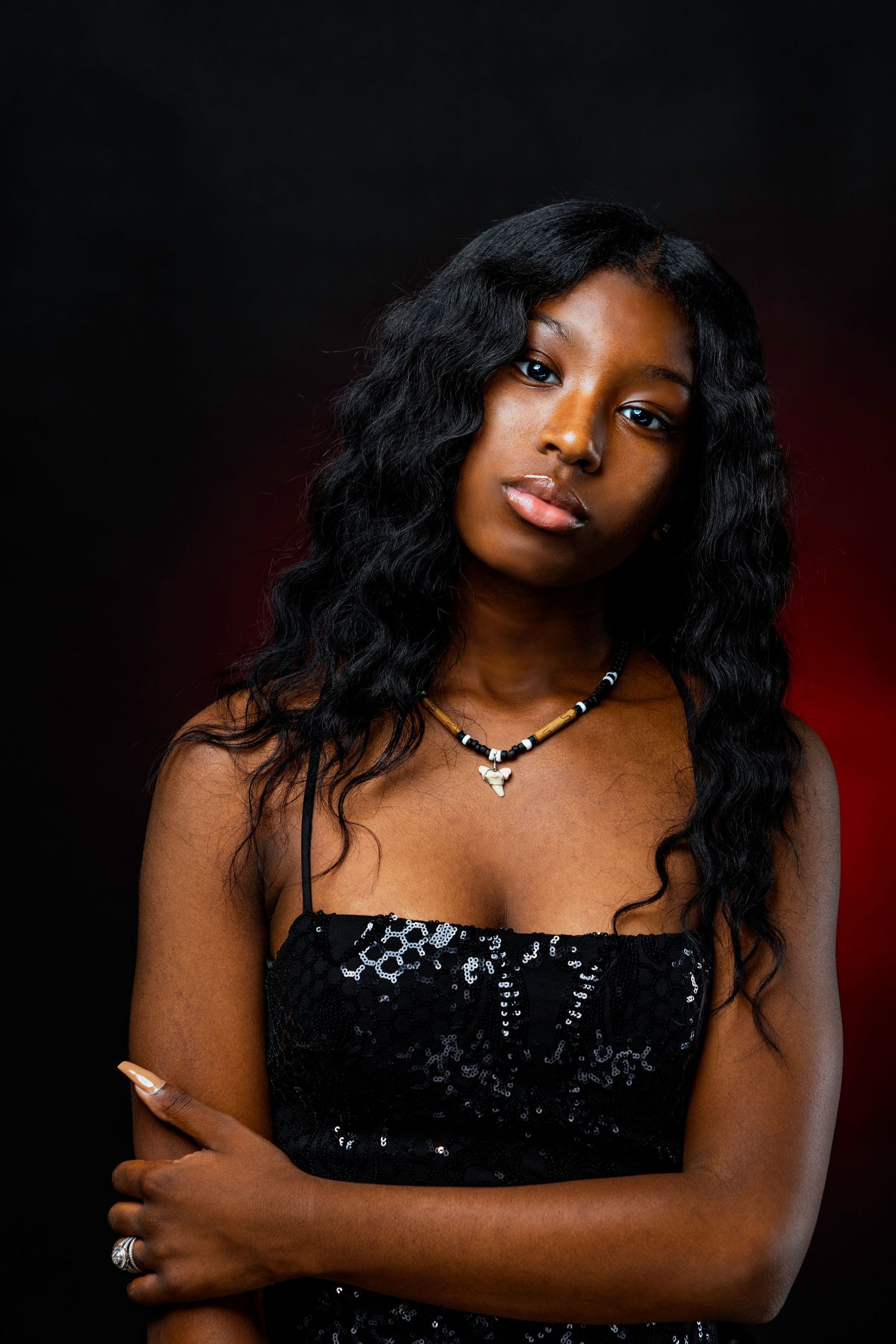 A dramatic portrait series featuring someone in a black sequined dress against a dark red background with moody lighting.