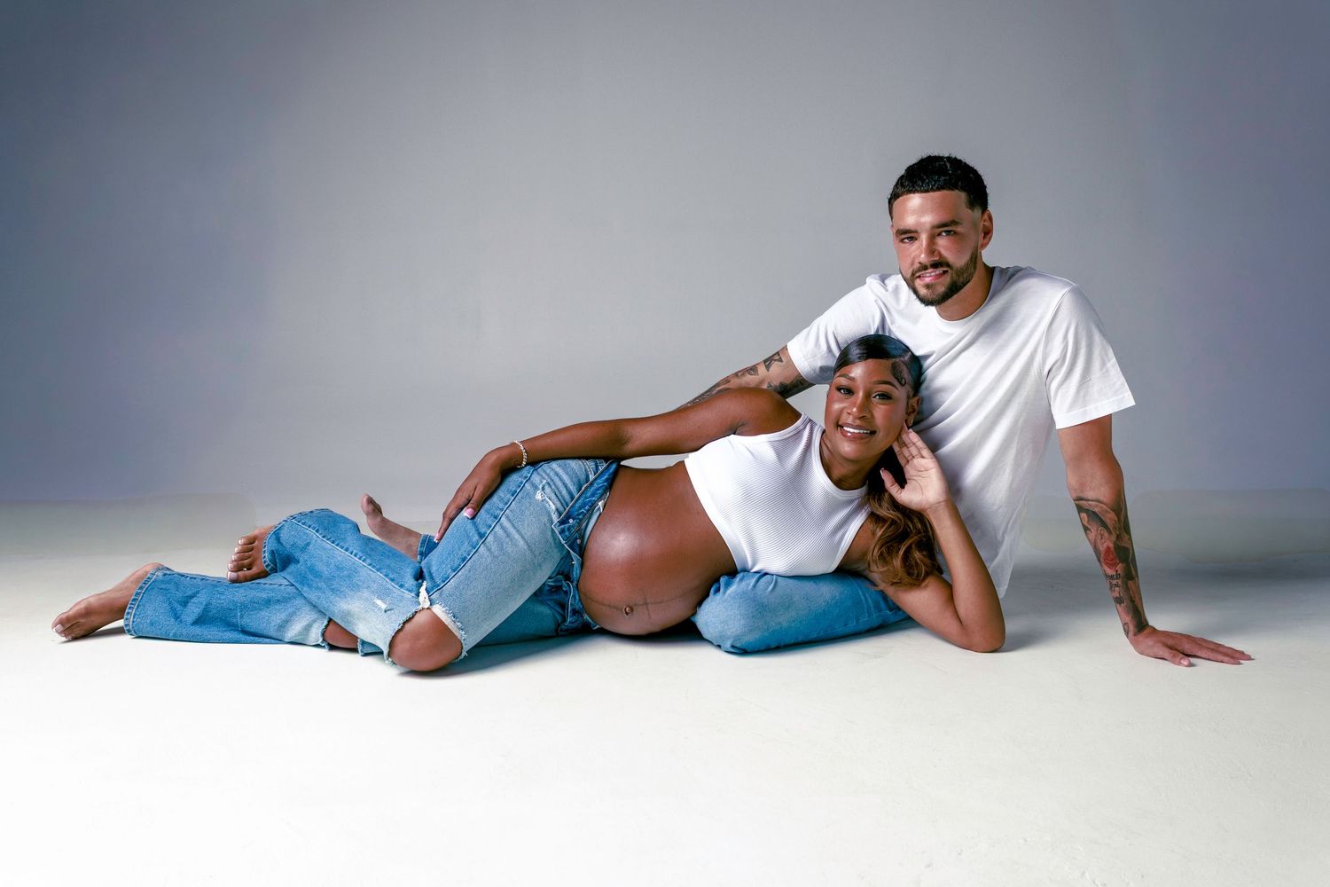 Person wearing light blue jeans and white t-shirt poses lying down in different positions on white backdrop.