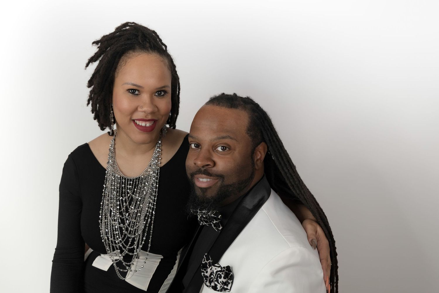 Elegant couple posing for formal portrait against white studio background.