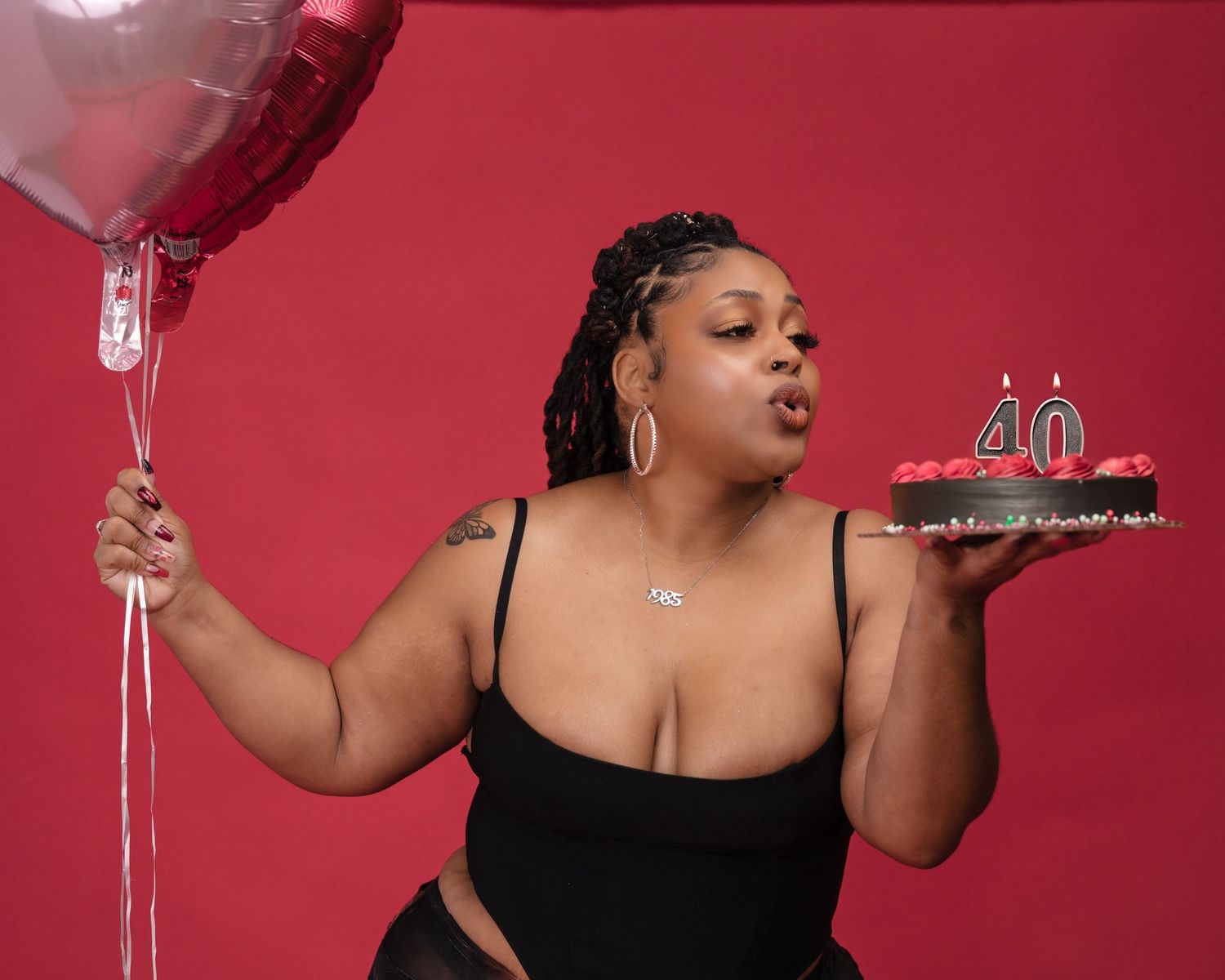 A celebratory birthday photo with balloon and cake against a red backdrop.
