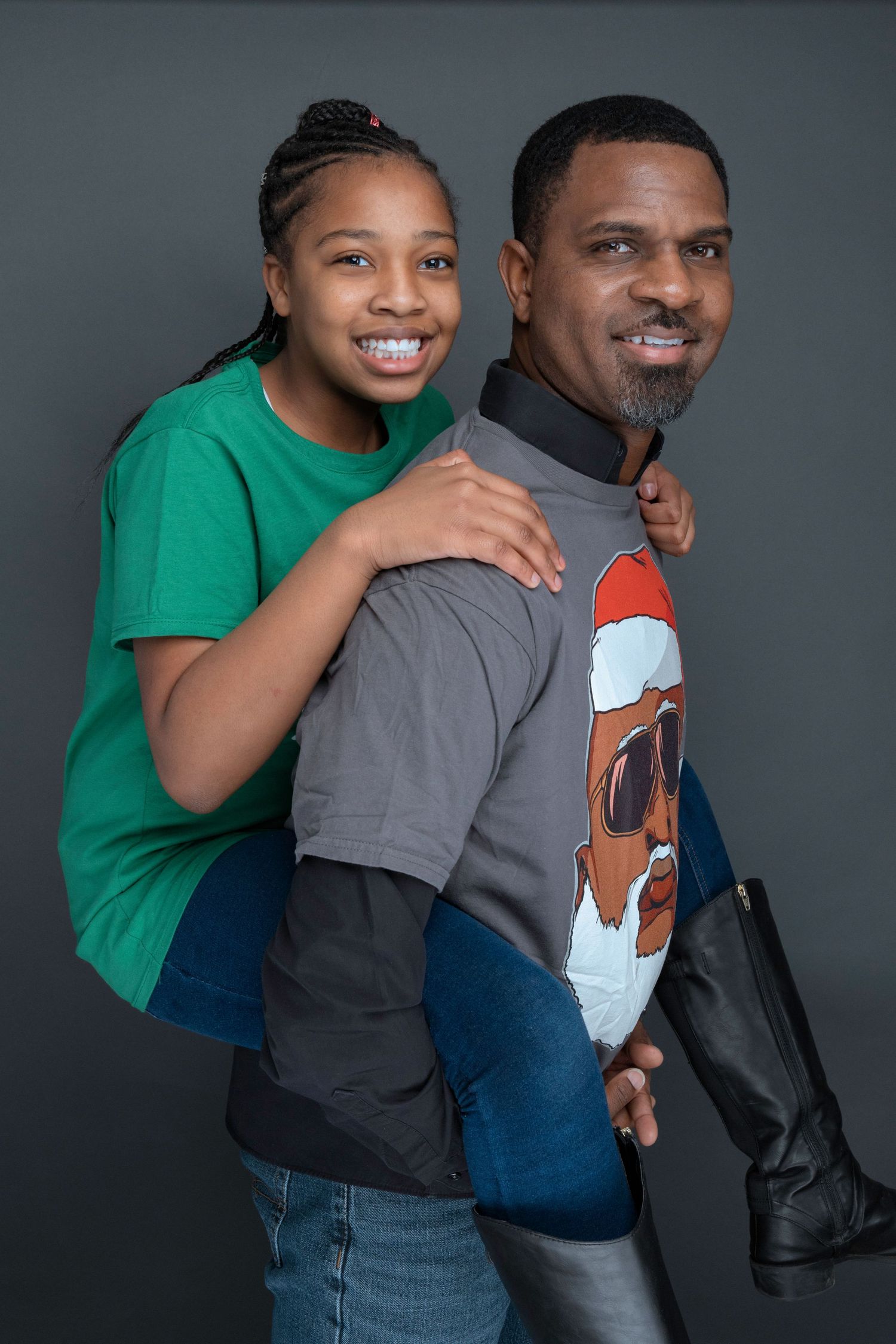 Playful piggyback pose of father and daughter in casual attire.