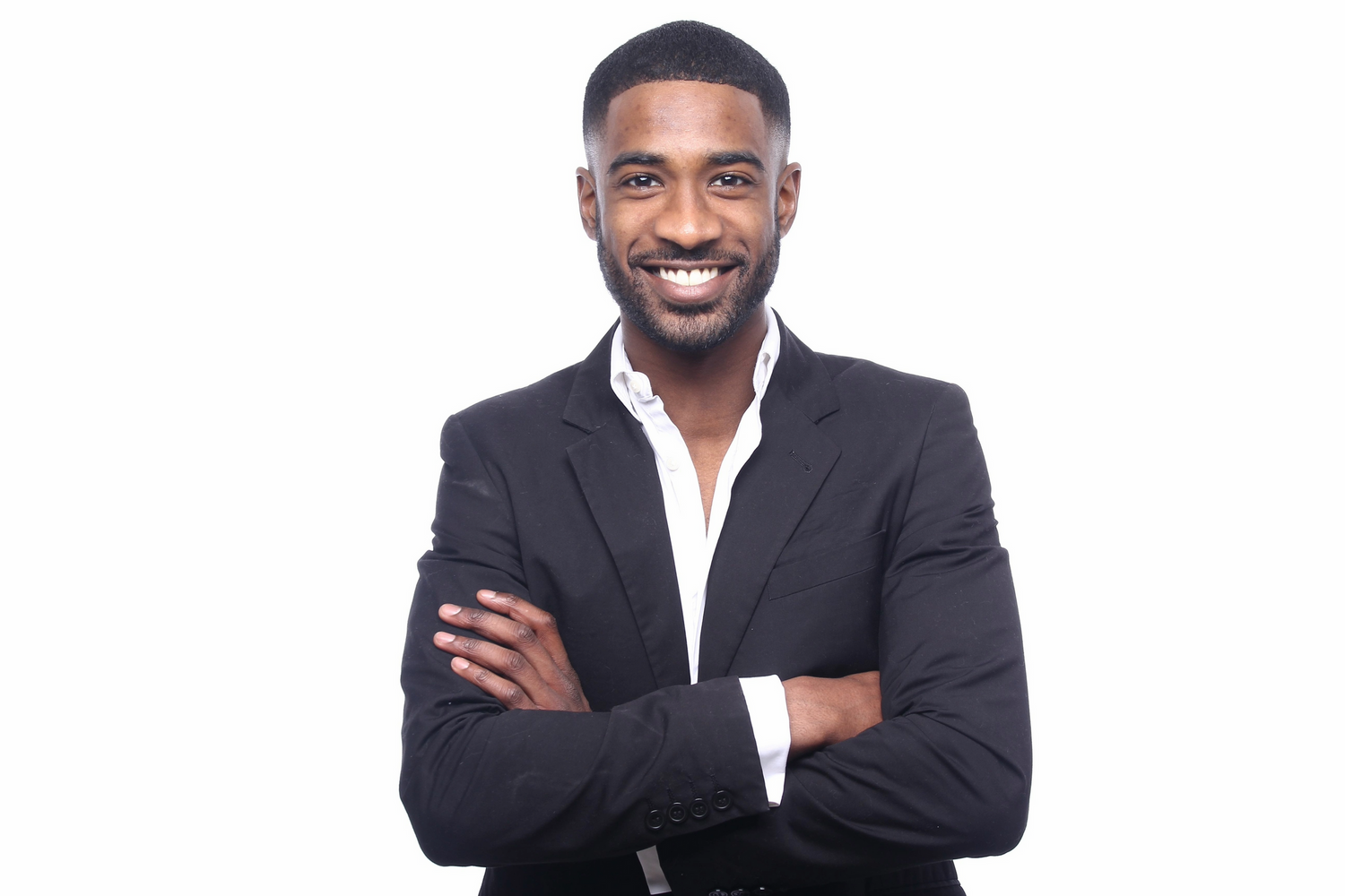 Professional in dark blazer and white shirt standing with arms crossed and smiling against white background.
