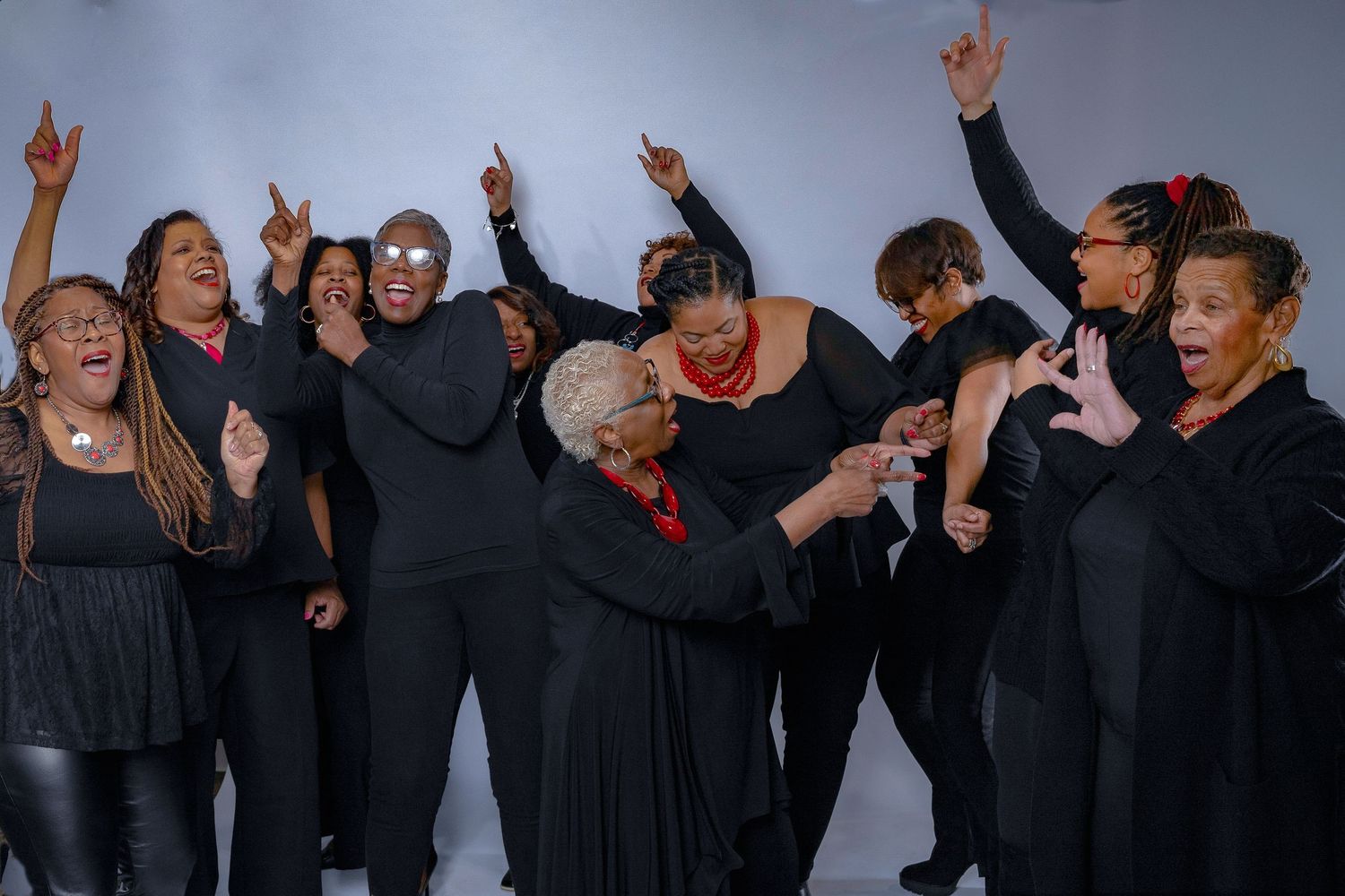 Group of performers in black clothes dancing and raising their arms energetically on stage.