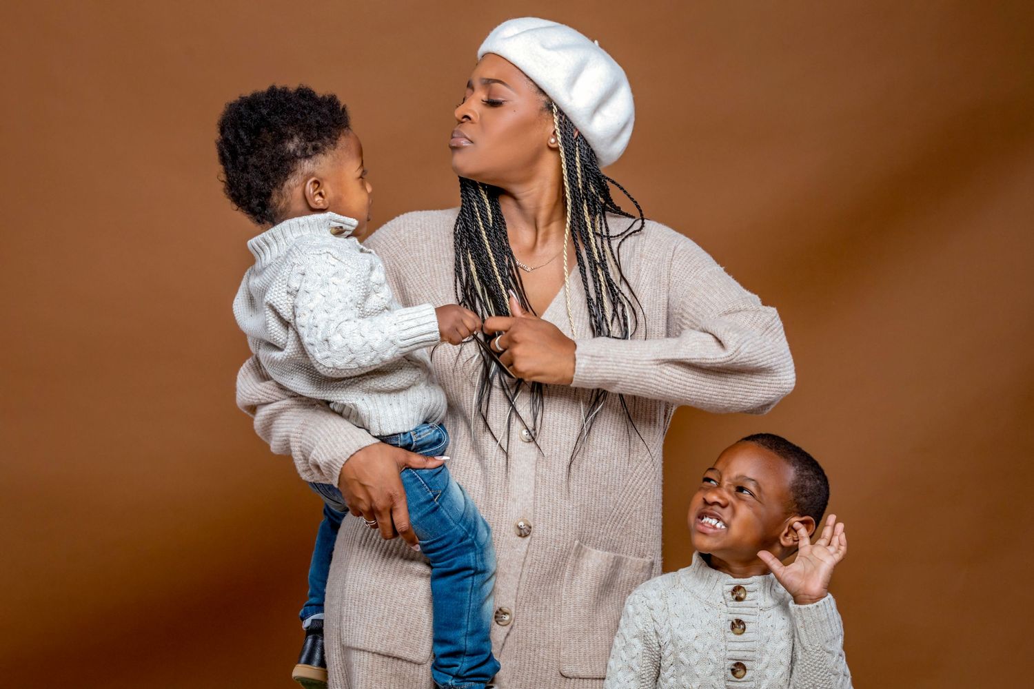 Candid family moment with playful expressions against brown backdrop.