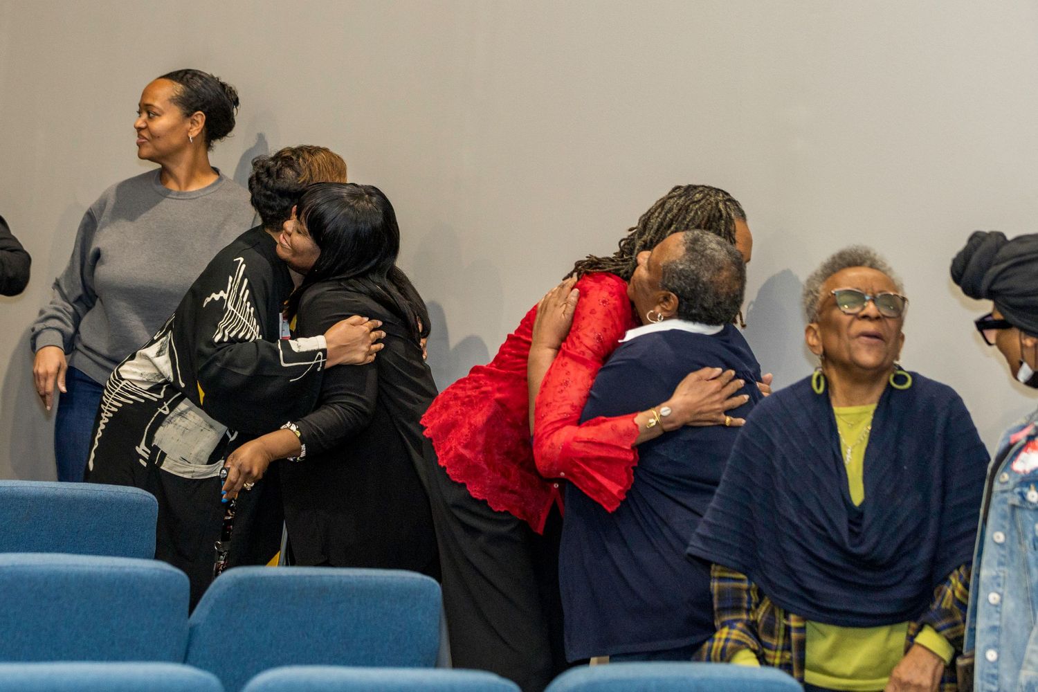 People embrace and gather together in a church during an emotional moment.