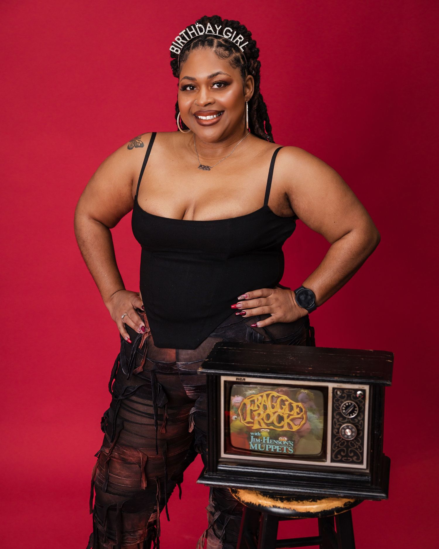 A stylish portrait featuring a vintage TV prop against a red background.