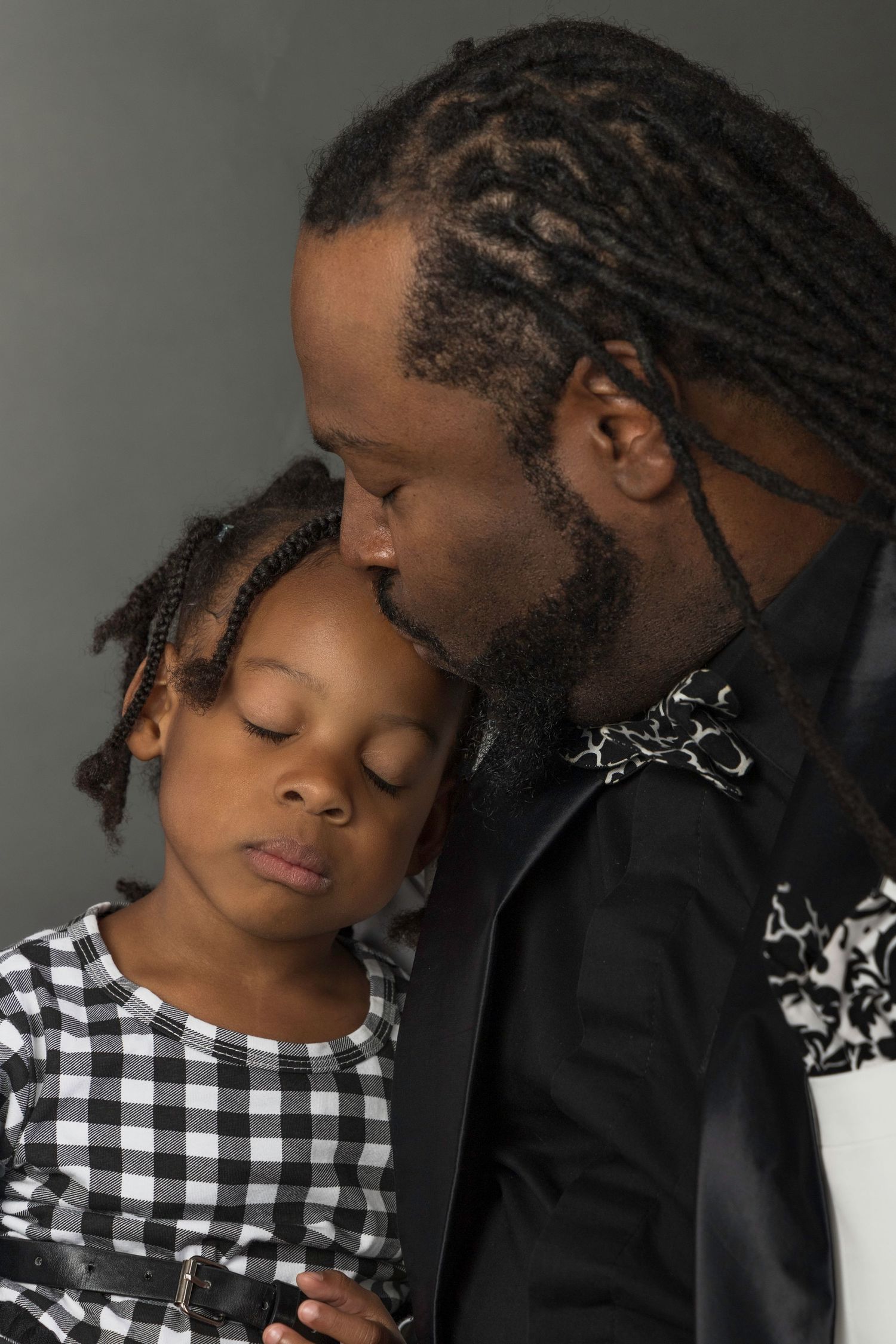A tender moment captured in a portrait showing parental love and affection, with a checkered dress and black jacket.