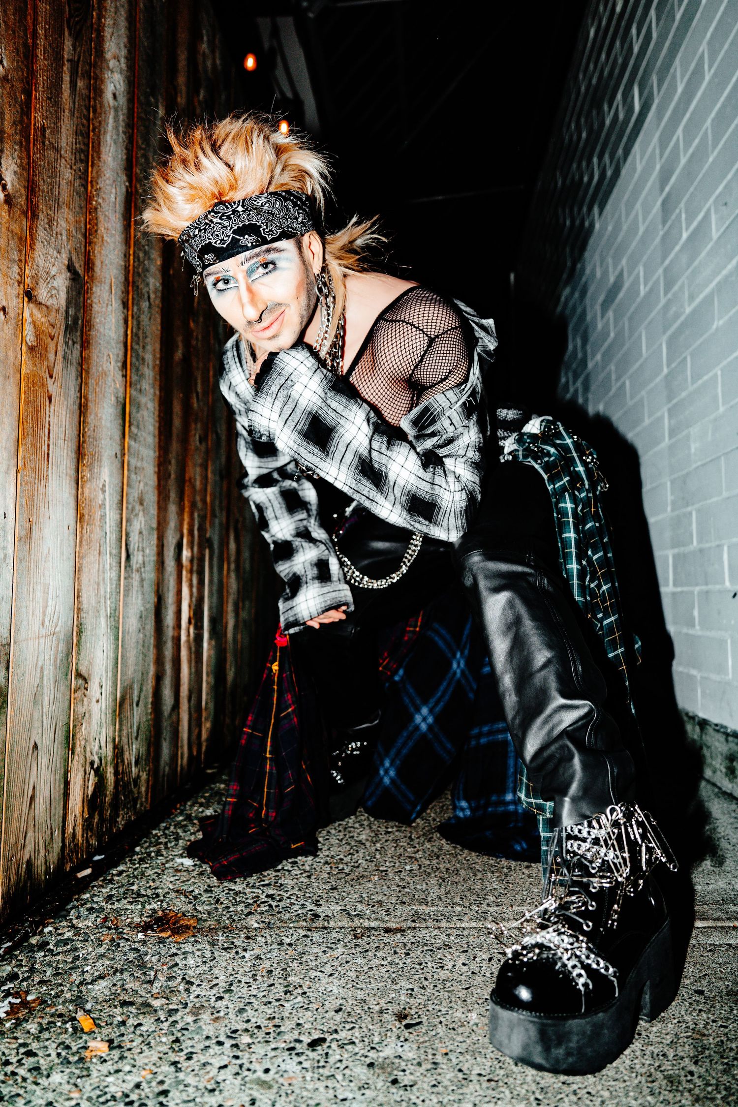 drag performer crouched down, foot towards camera and hand resting on chin