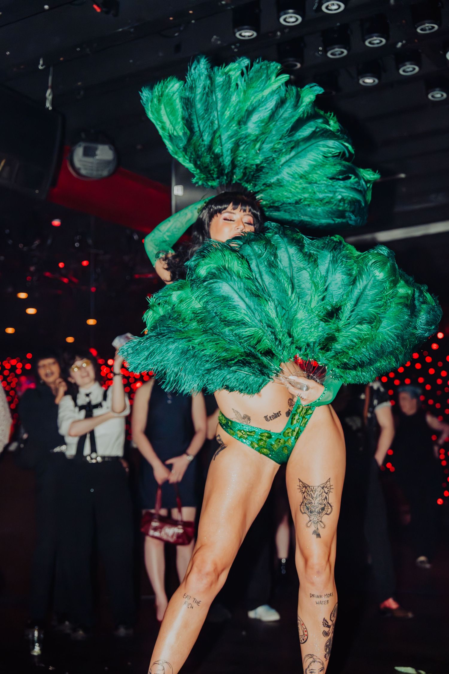burlesque performer with green fans, performing to the camera