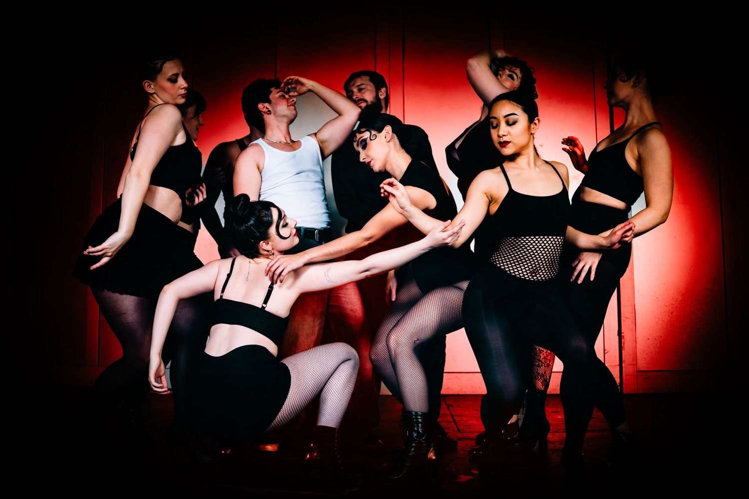 a group of dancers dancing, dark and red in the background