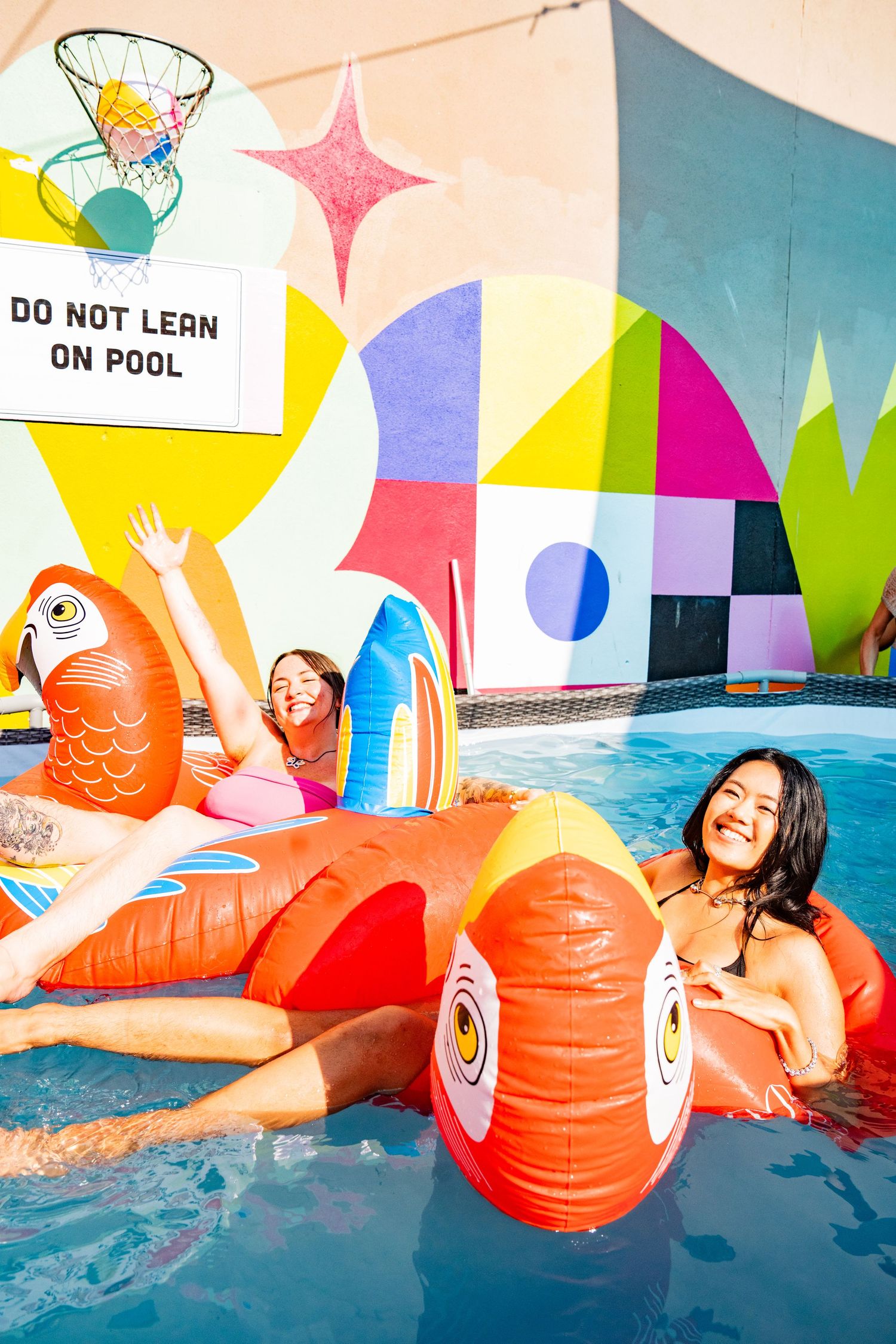 two people in a pool on floaties posing to the camera