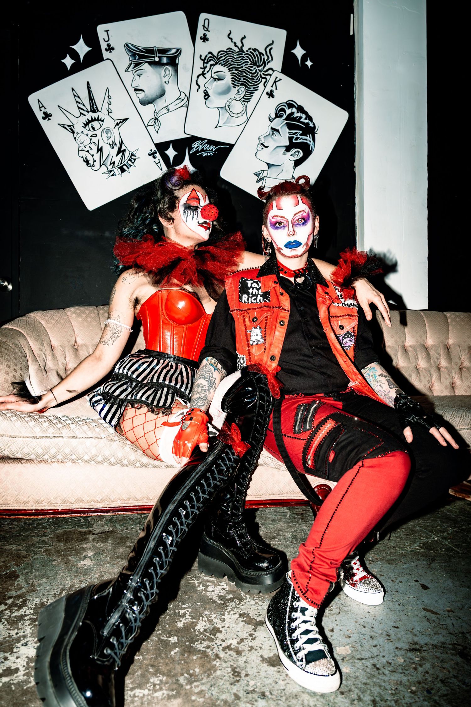 two performers sitting on a couch, posing towards the camera