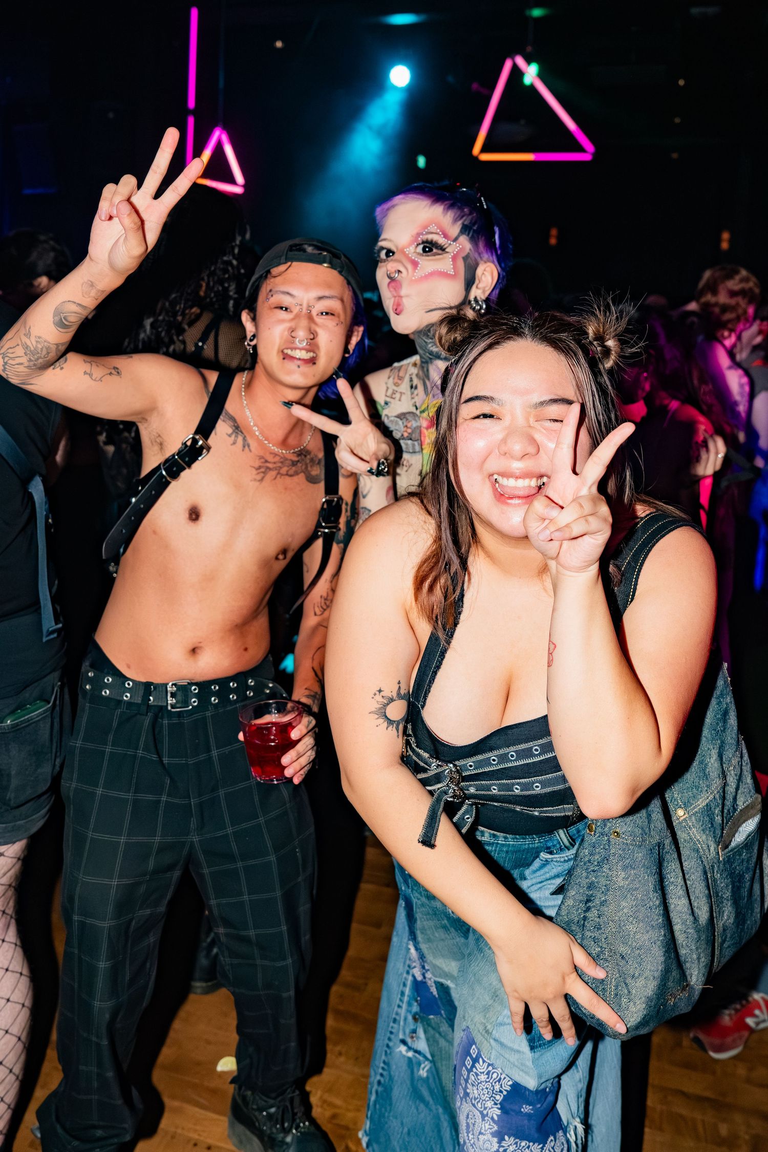 three people posing, two with peace signs and one just smiling