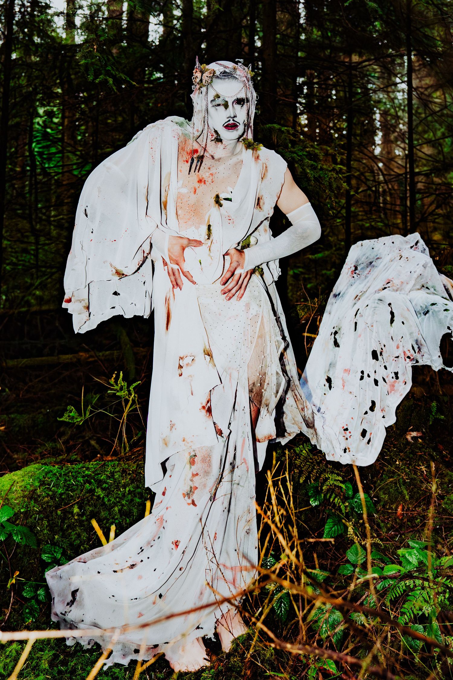 in the woods, with the performer posing, in all white