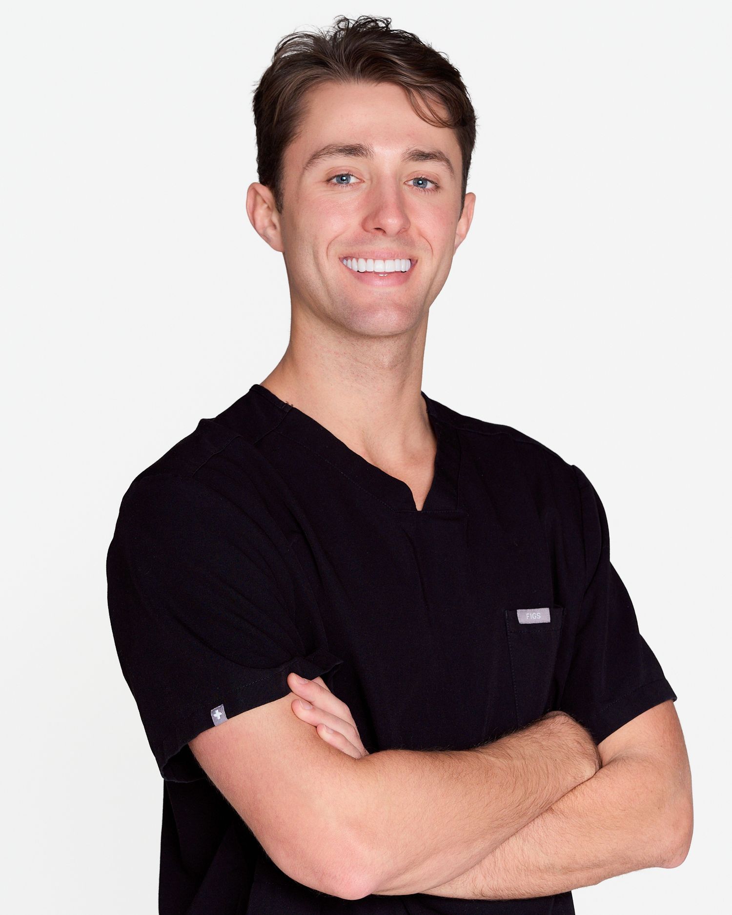Smiling male healthcare professional in black scrubs with arms crossed against white background.
