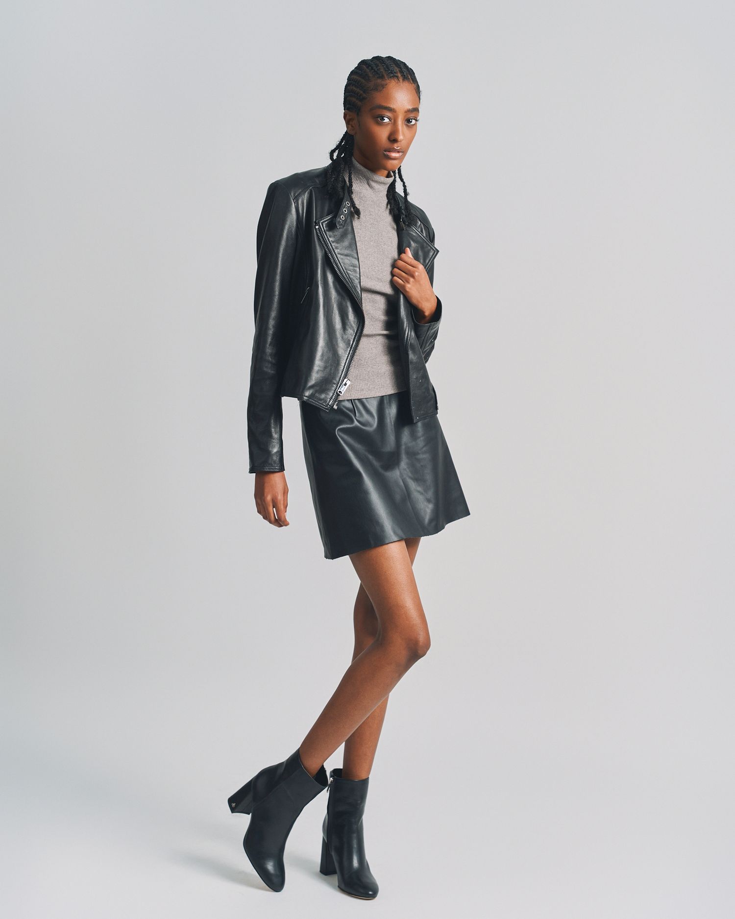 Model in black leather jacket and shorts poses against white background showing different angles and stances.