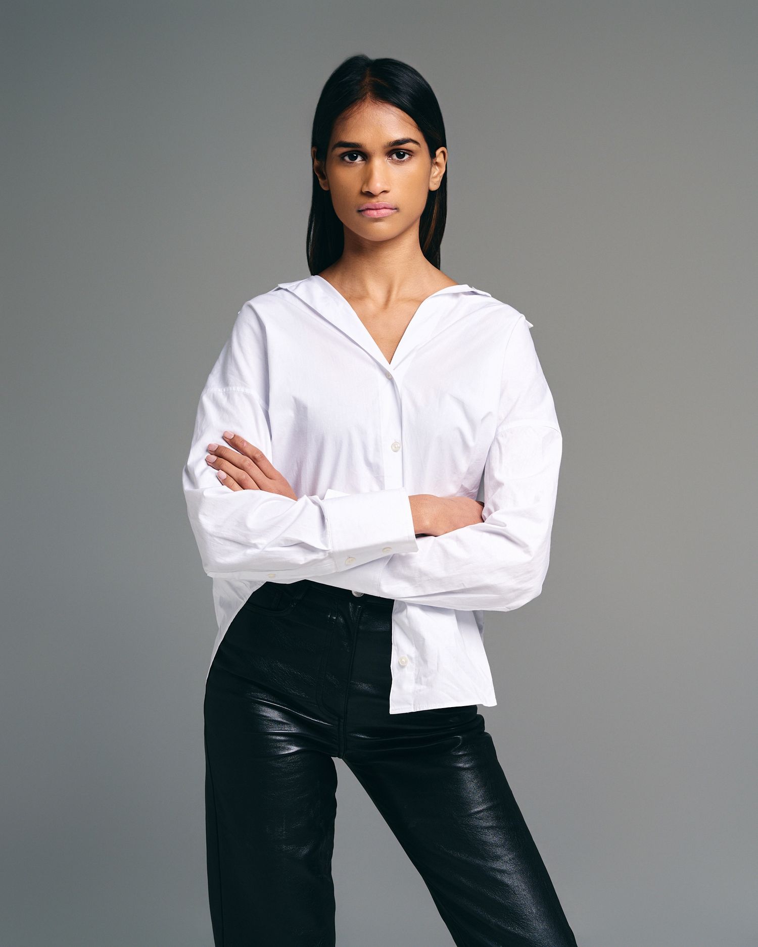 Professional studio shot of model in white button-down shirt and black leather pants.