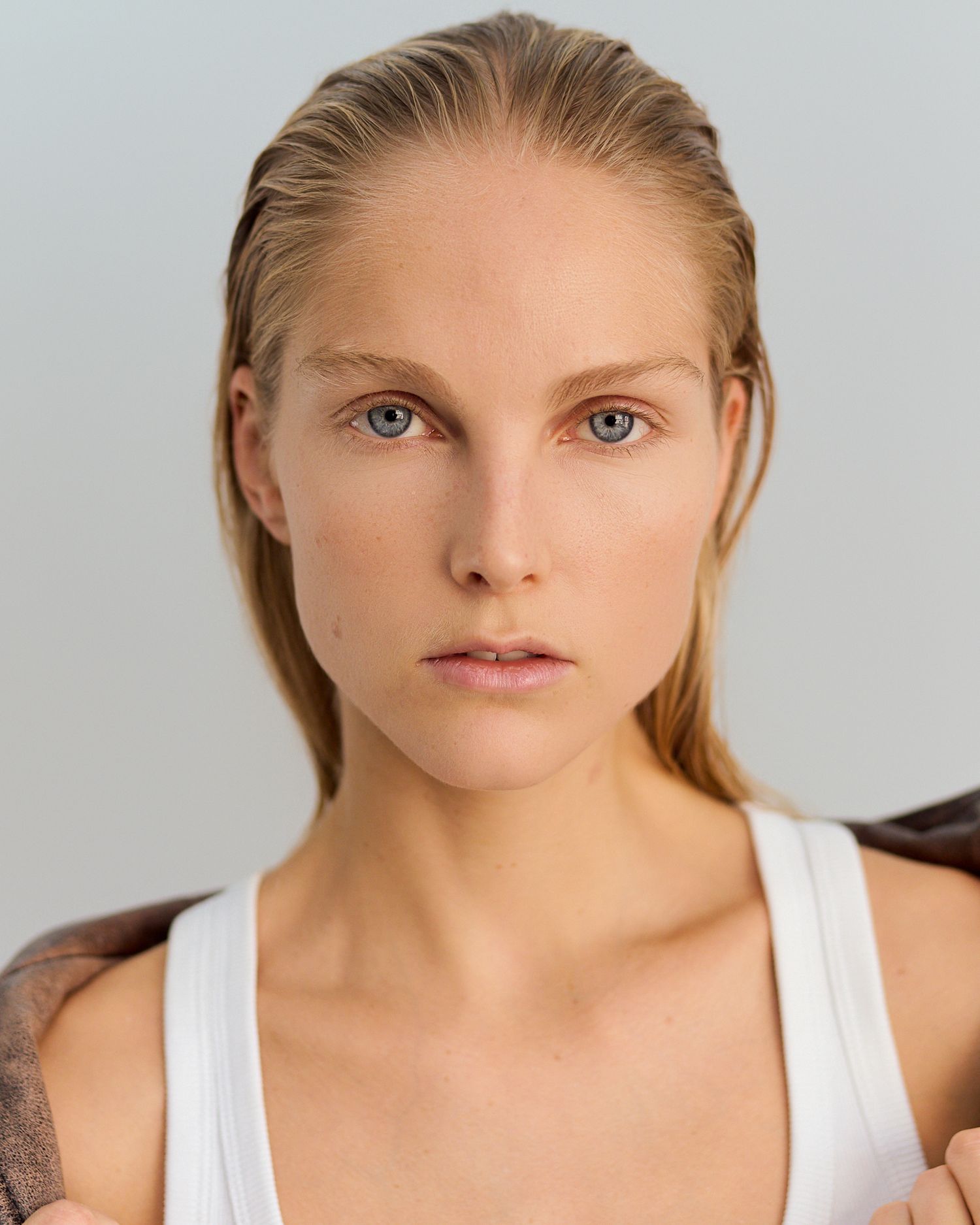 Close-up portrait series of a person with wet hair wearing a white tank top against a light background.