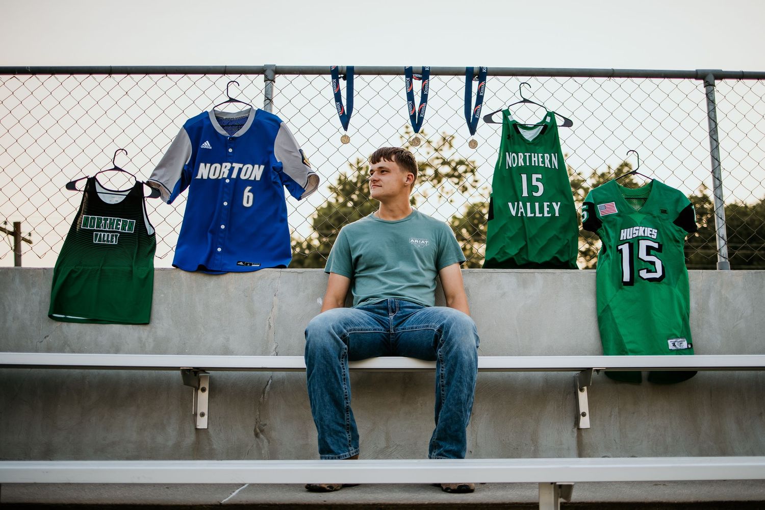 Sports jerseys and uniforms displayed on a concrete wall with metal fence mounting.