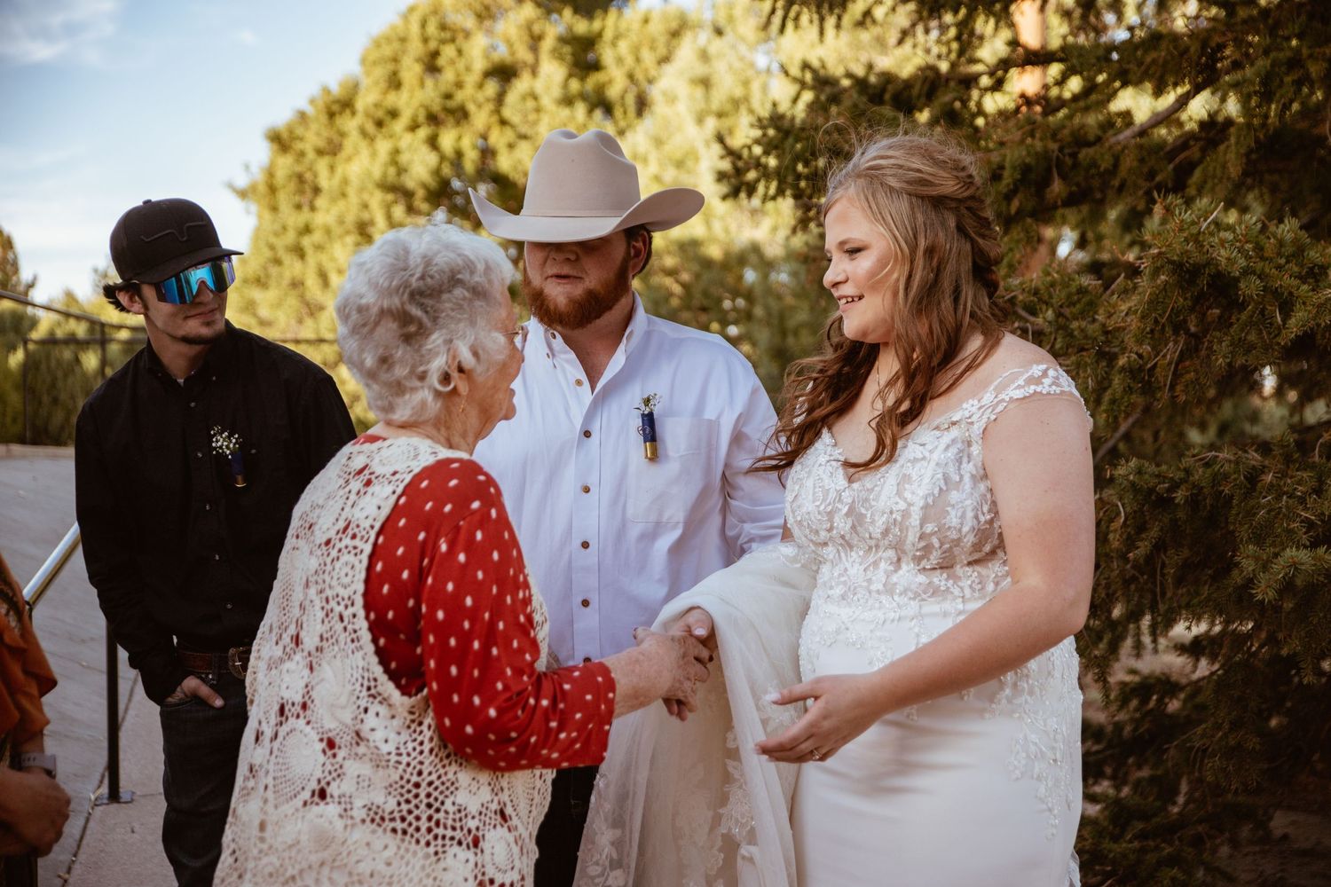A countryside wedding ceremony with guests in traditional western attire.