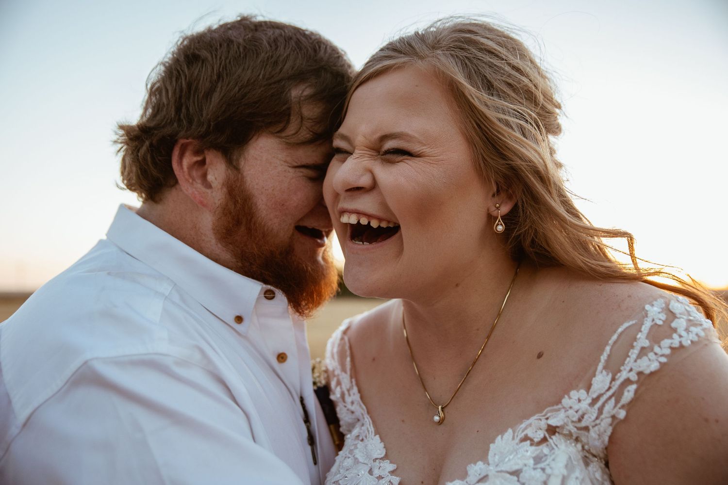 A joyful candid moment shared between newlyweds outdoors.