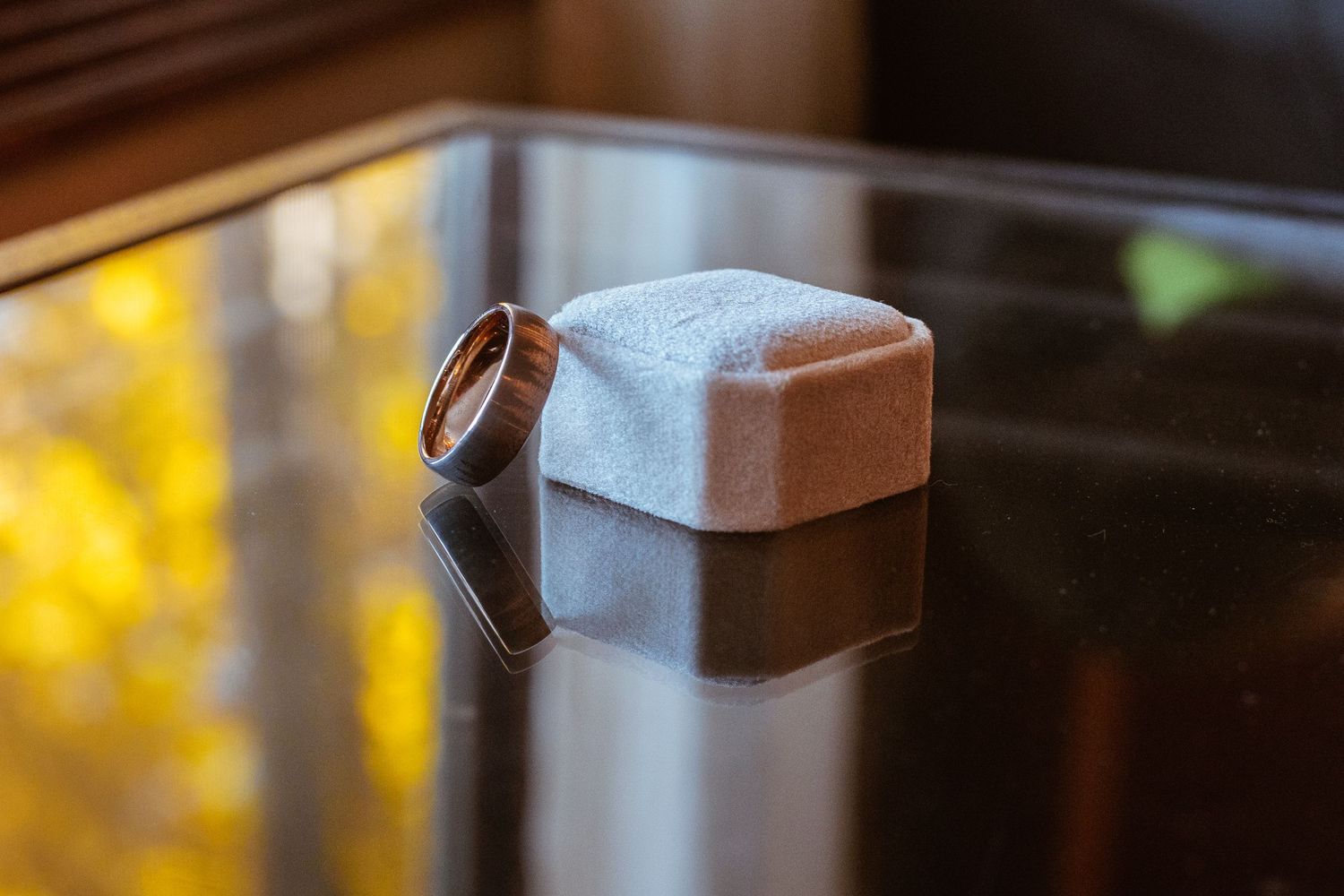 A wedding ring resting on a reflective surface with soft lighting.