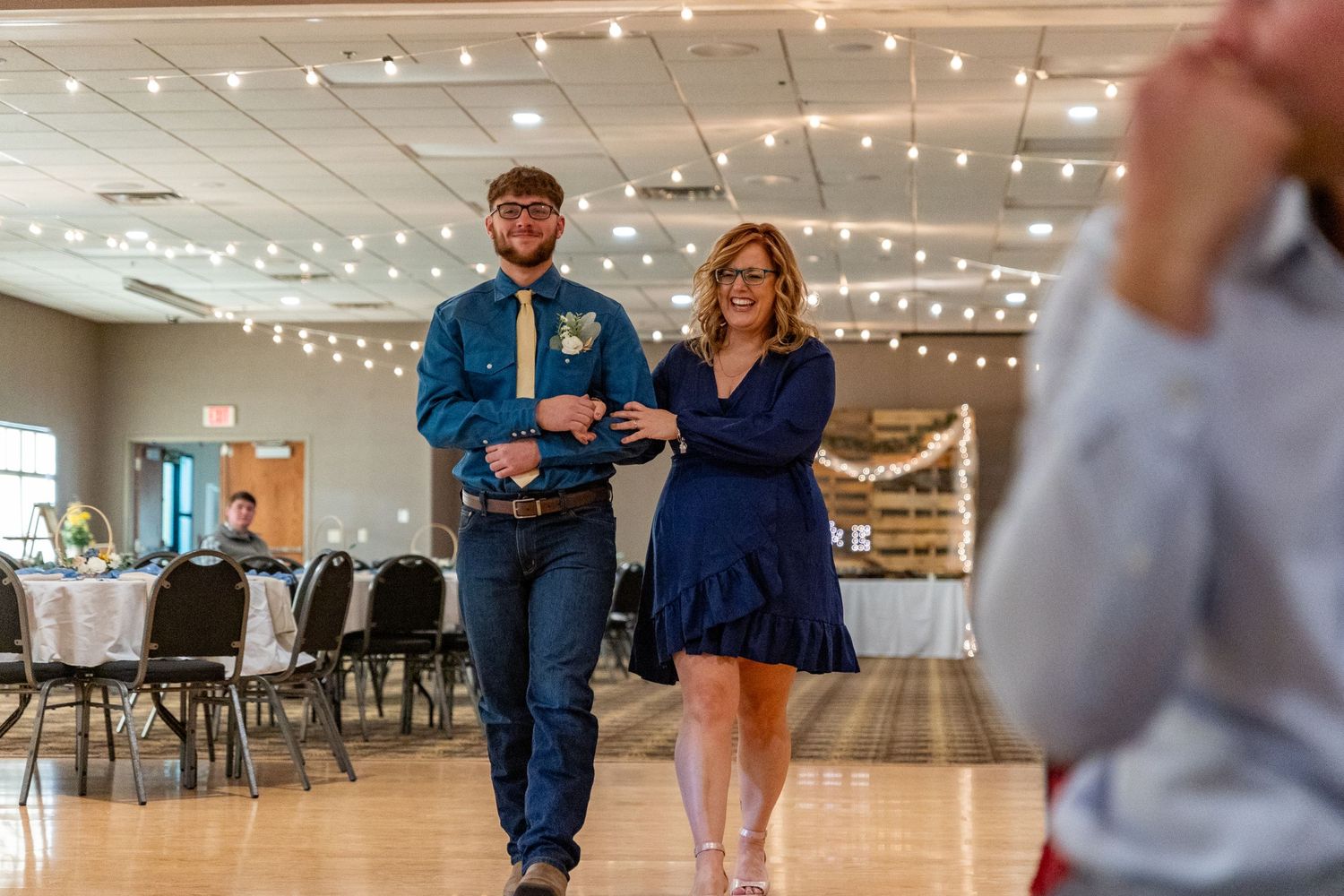 Wedding reception scene with string lights and guests dancing in celebration.