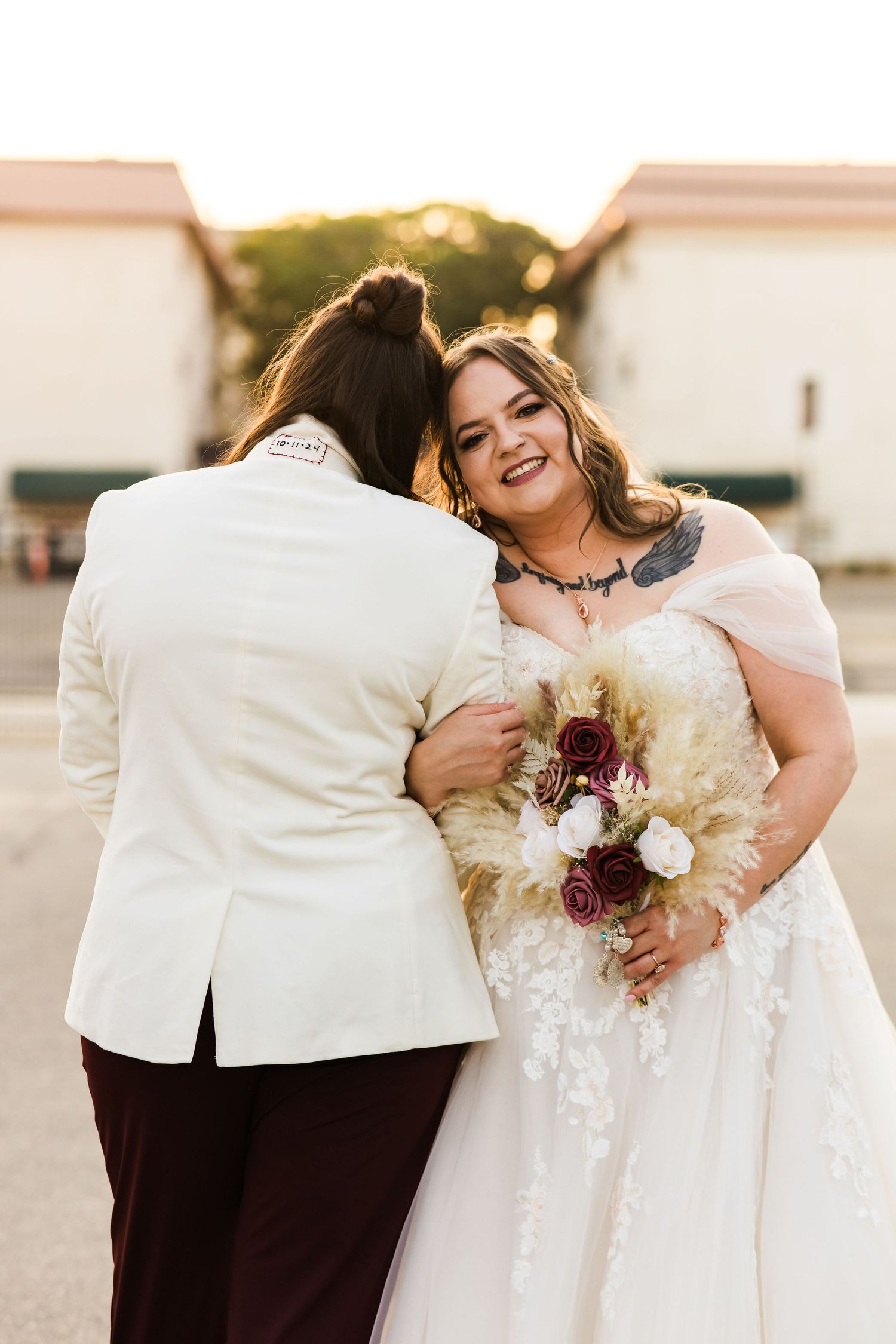 A tender moment between a couple in wedding attire with a bouquet of white and burgundy flowers.