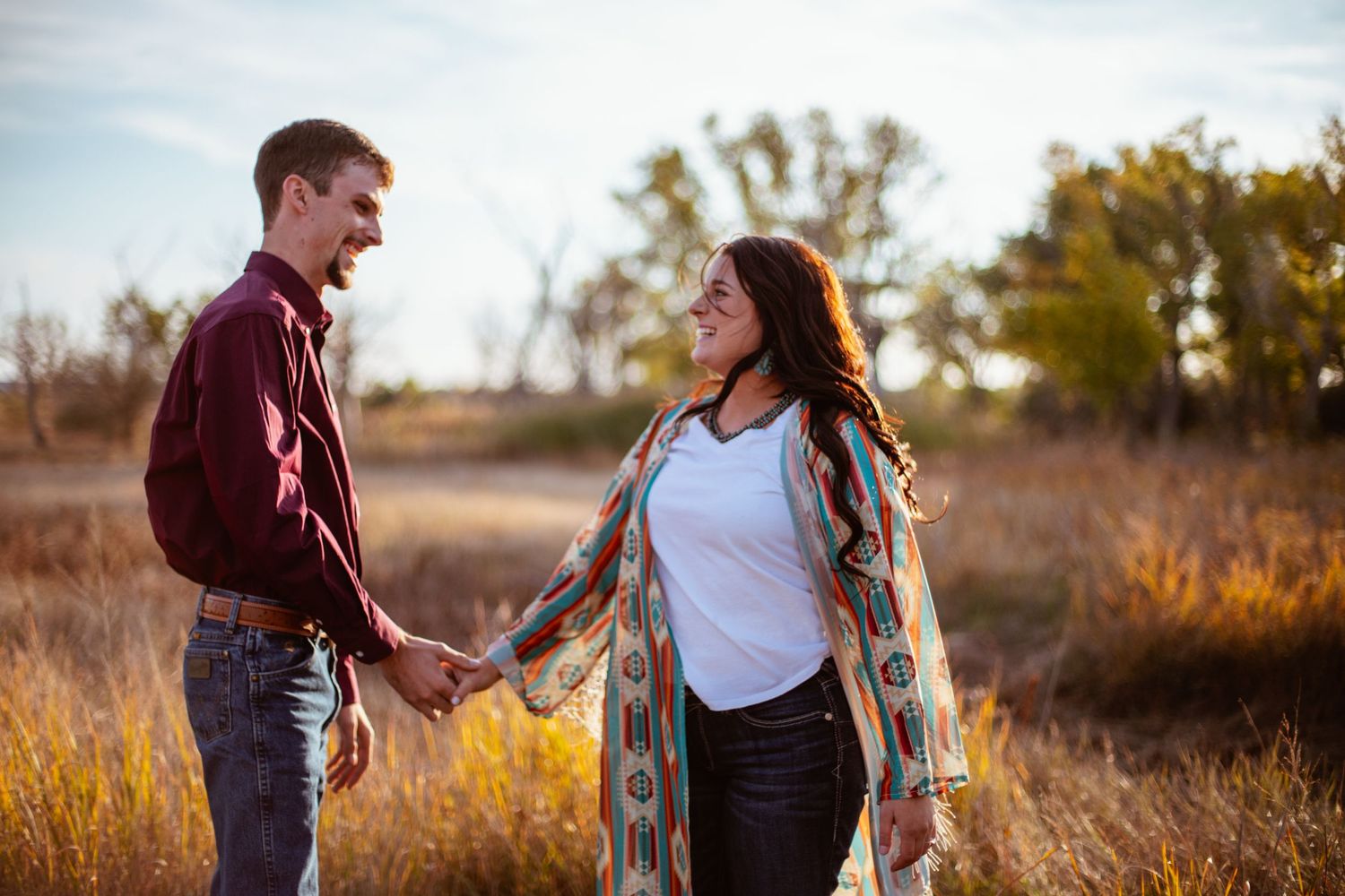 Romantic couple shares tender moment in golden autumn field during sunset.