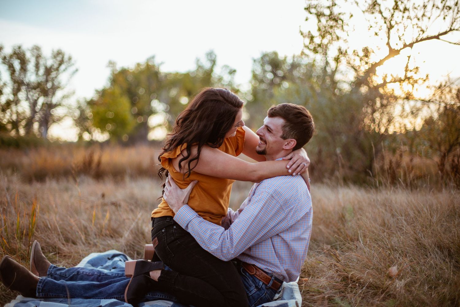 Intimate autumn engagement photo in golden grass field.