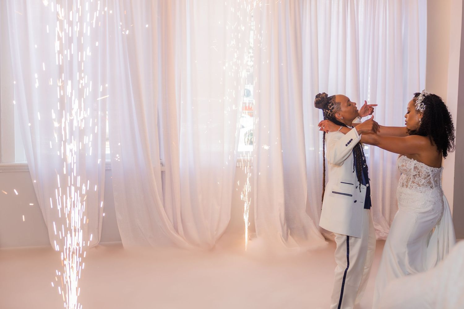 A romantic wedding ceremony moment captured under flowing white drapery and sparkling lights.