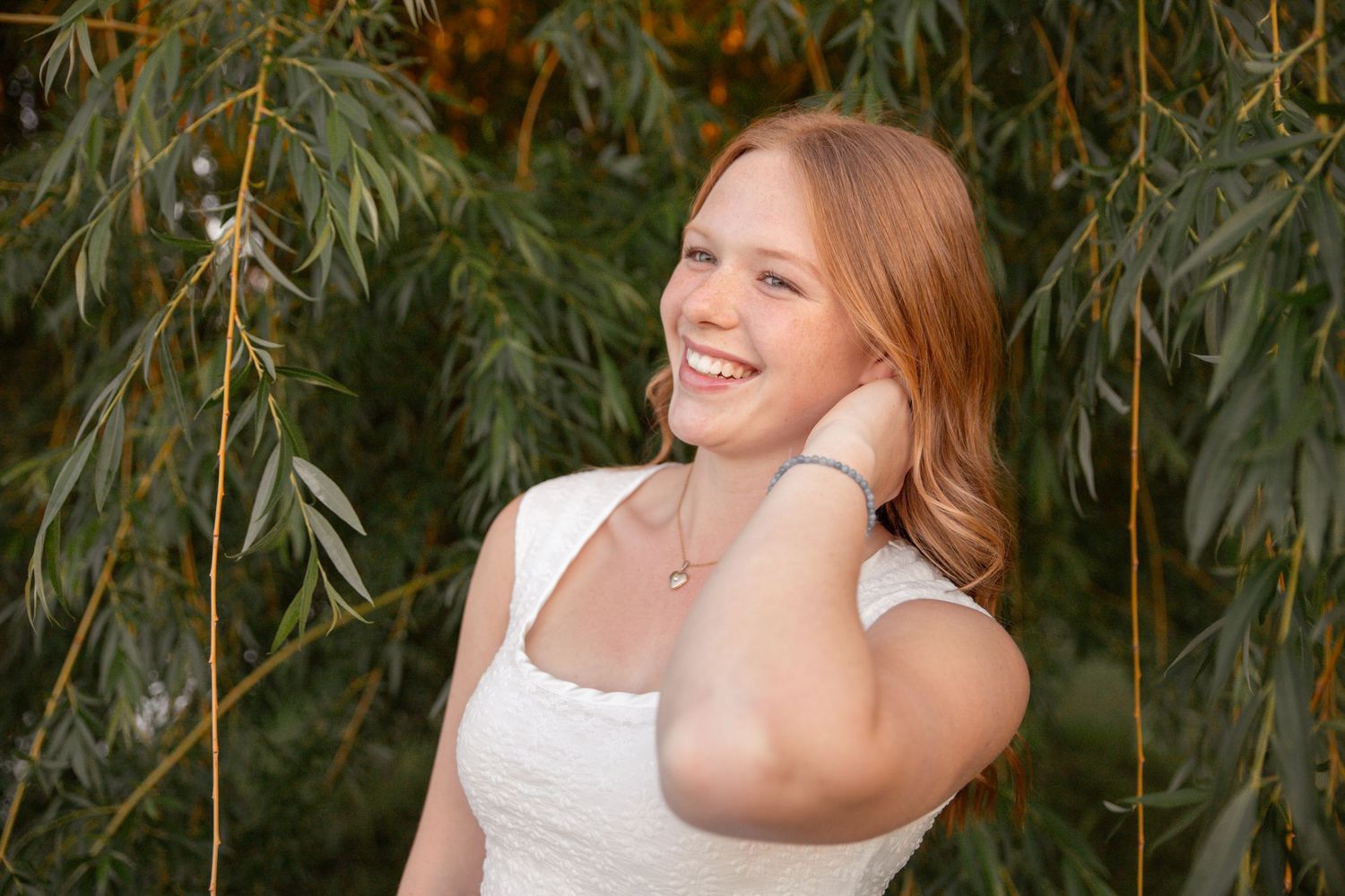 Outdoor portrait with natural lighting under willow tree branches.