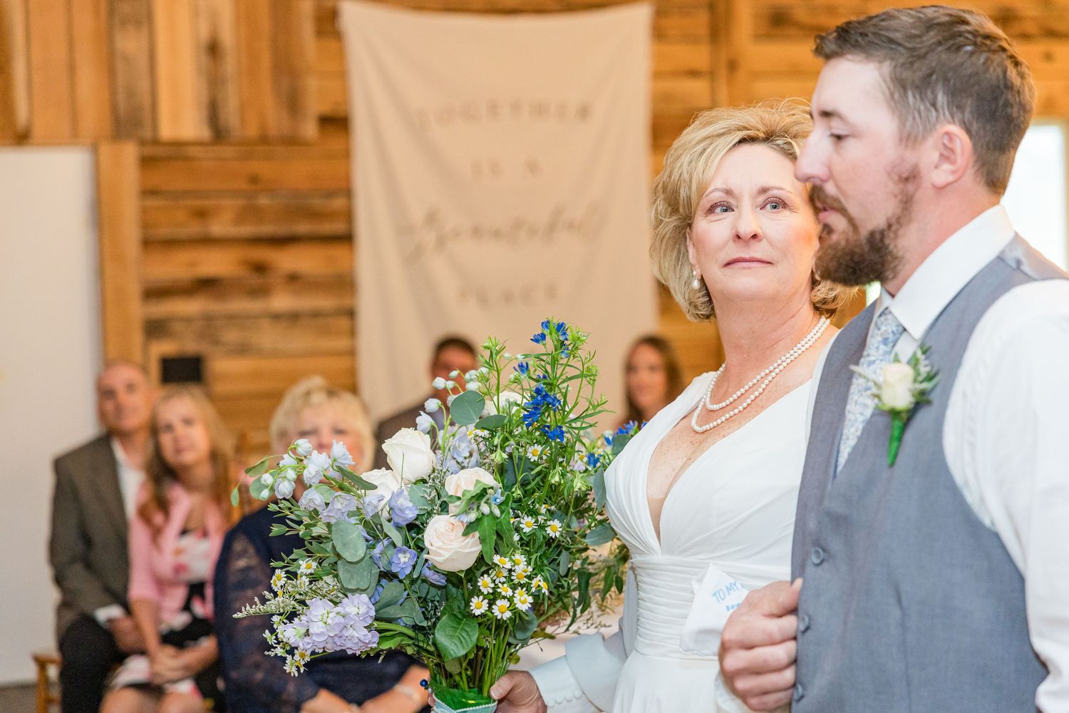 Wedding celebration with floral decorations in a rustic wooden barn setting.