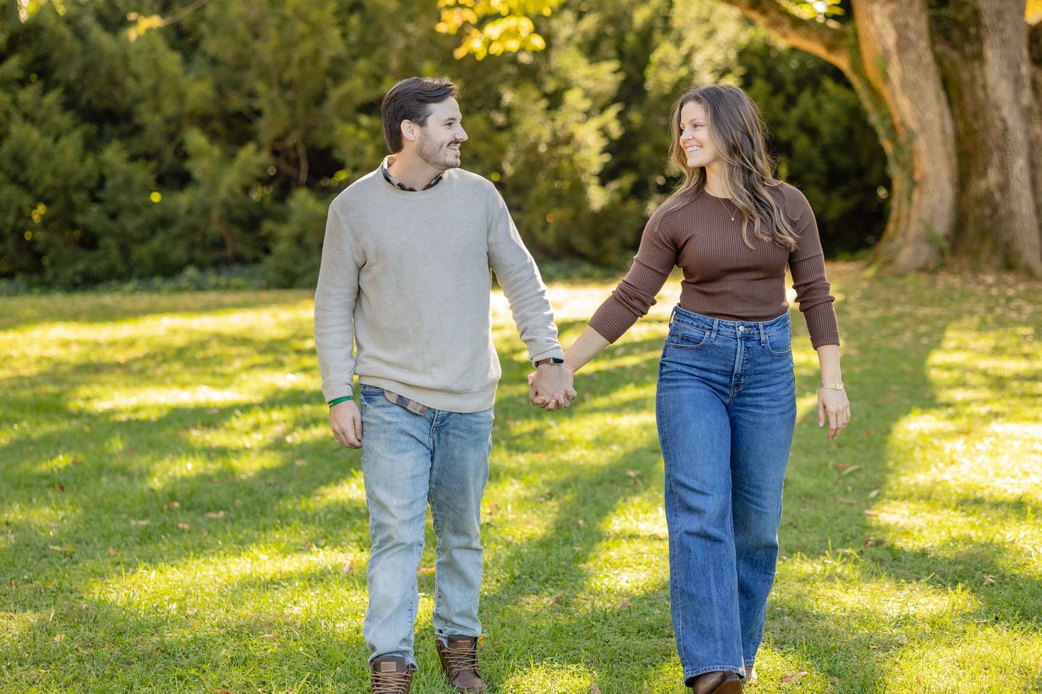 Couple walking together on sunlit grass wearing coordinated casual outfits.
