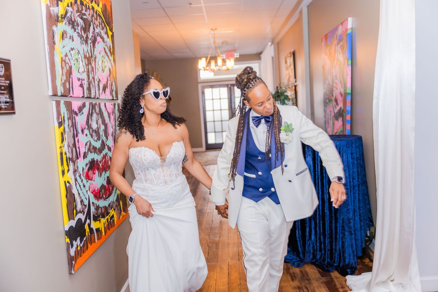 Wedding party members walking through an indoor venue decorated with colorful art on the walls.