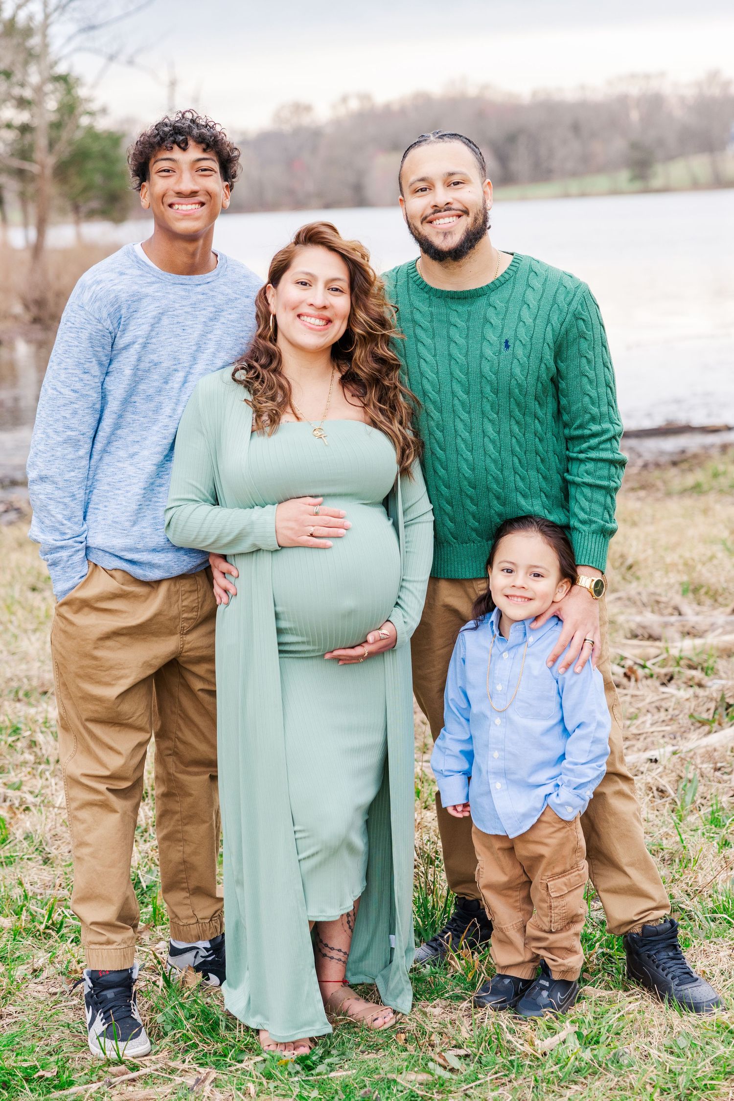 Family maternity photo session outdoors with mother in mint green dress and family in coordinating colors.
