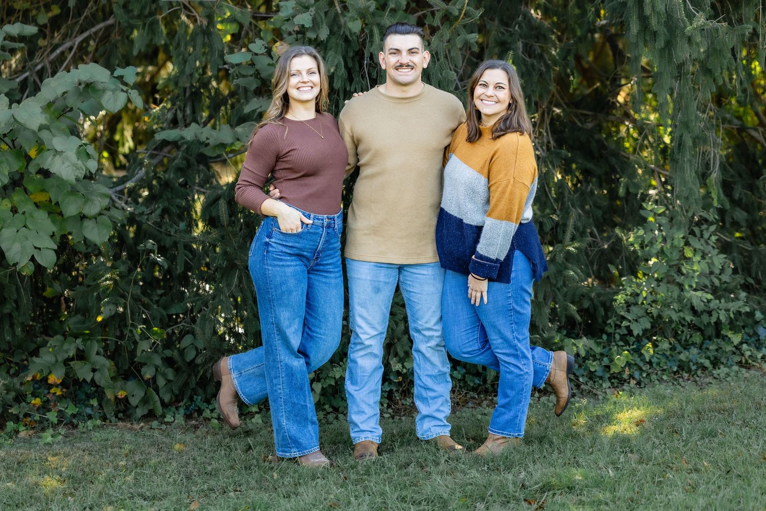 Family members wearing coordinated casual outfits pose against garden backdrop.