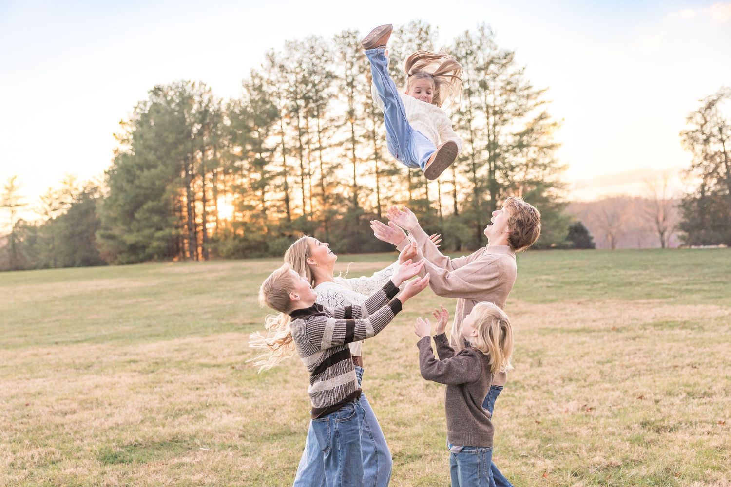 A couple playfully tosses confetti in a grassy field during sunset while celebrating together.