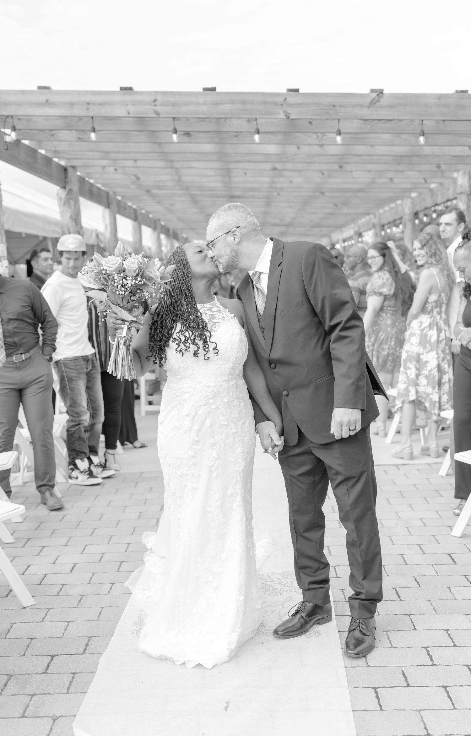 Wedding couple dances surrounded by guests under covered pavilion.