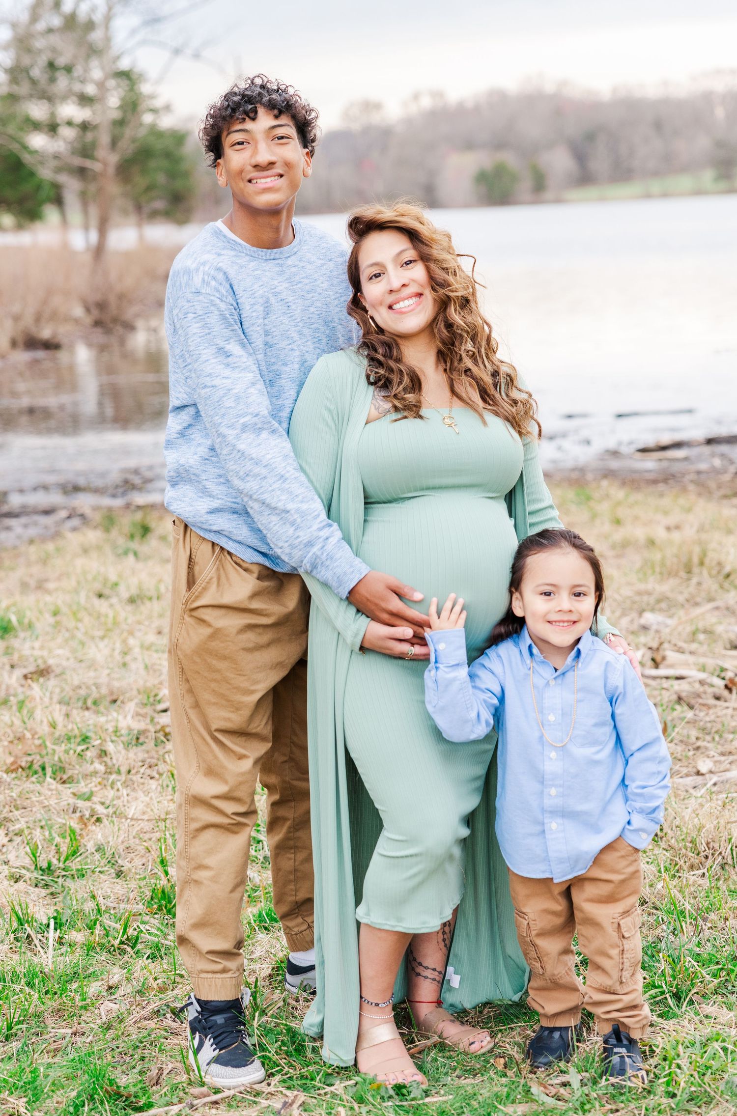 Maternity family photos outdoors with mother in mint dress and family in coordinating blue and khaki.