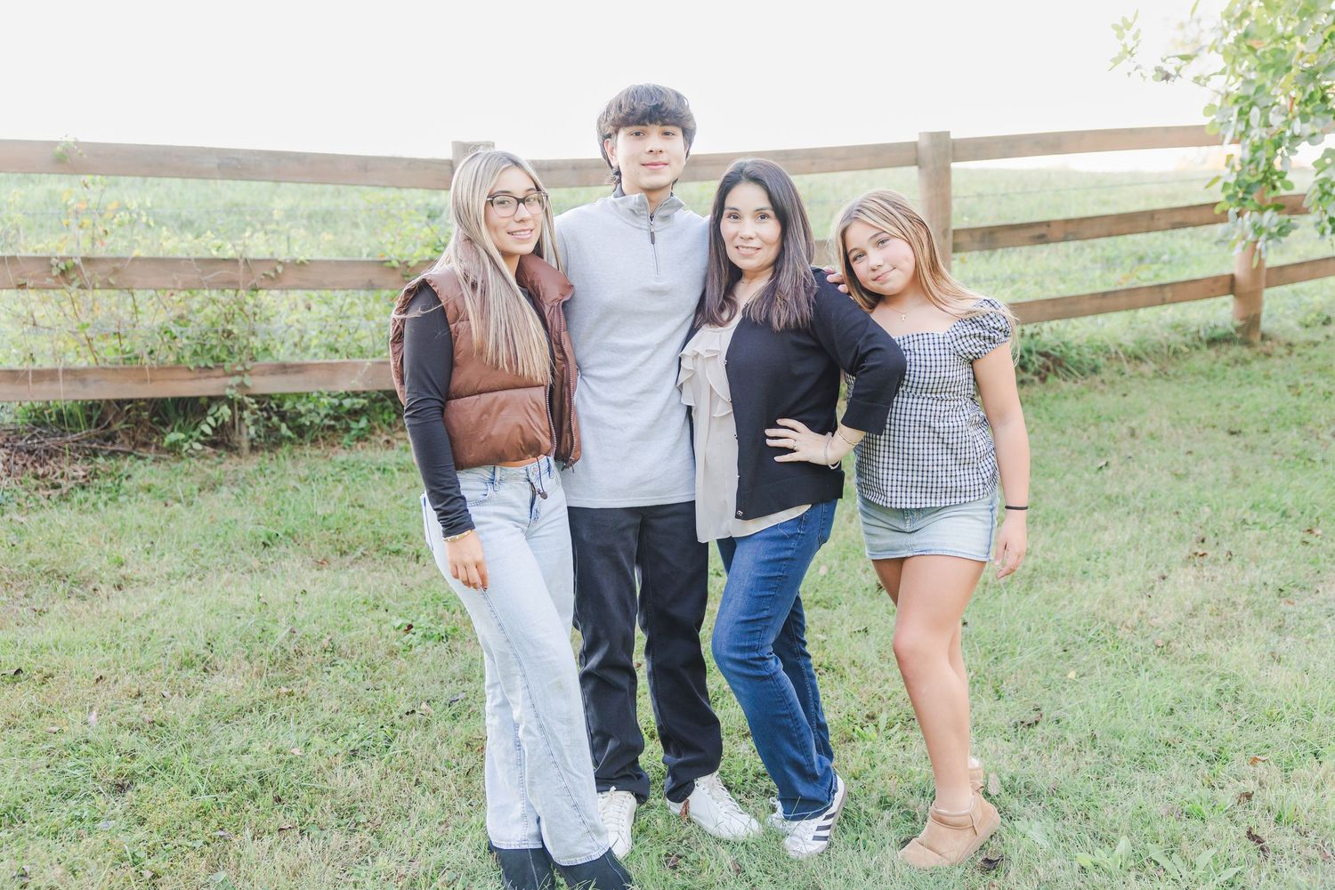 A group poses together outdoors on a grassy hill during golden hour.