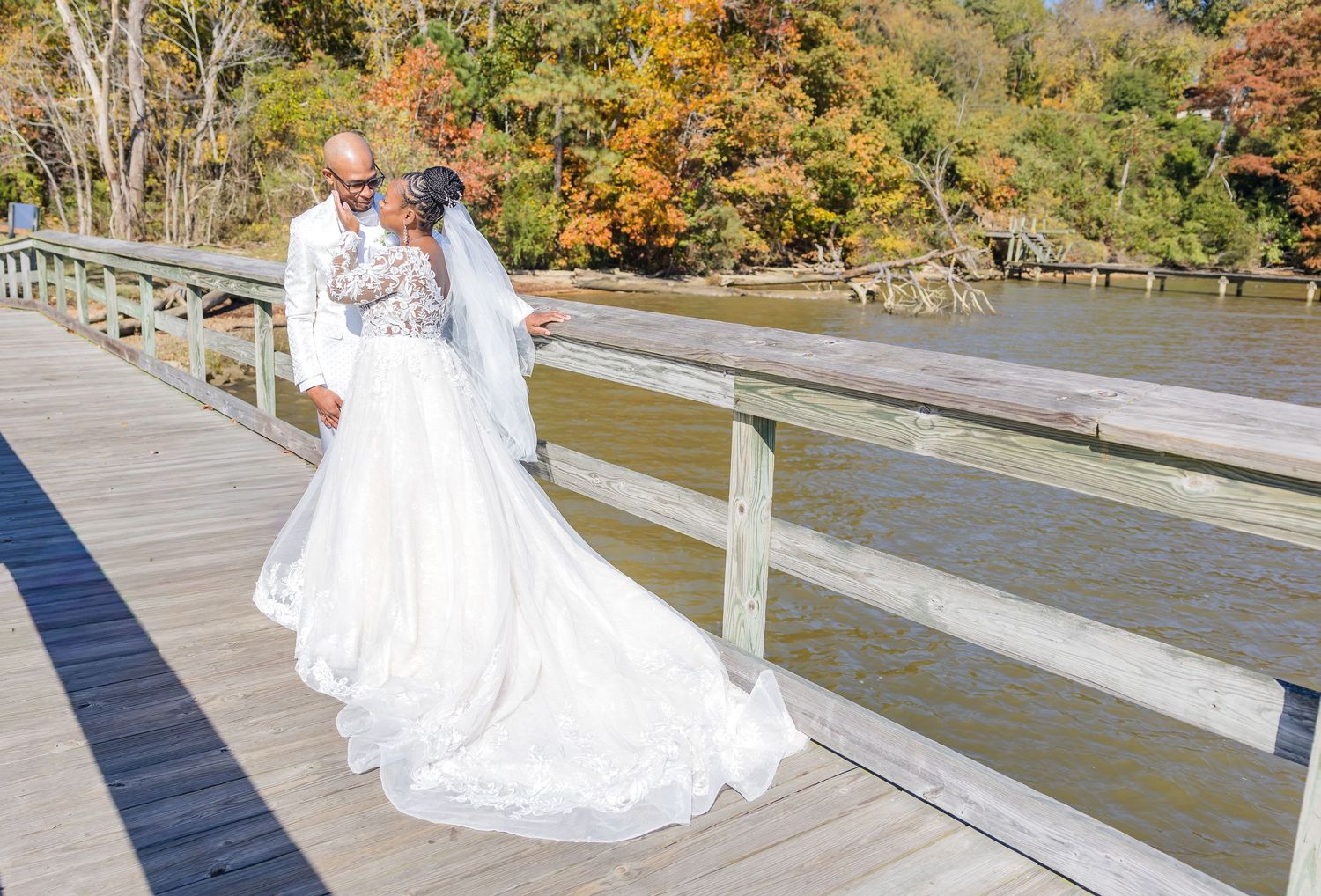 Scenic autumn wedding photos on a wooden boardwalk surrounded by fall foliage and golden trees.