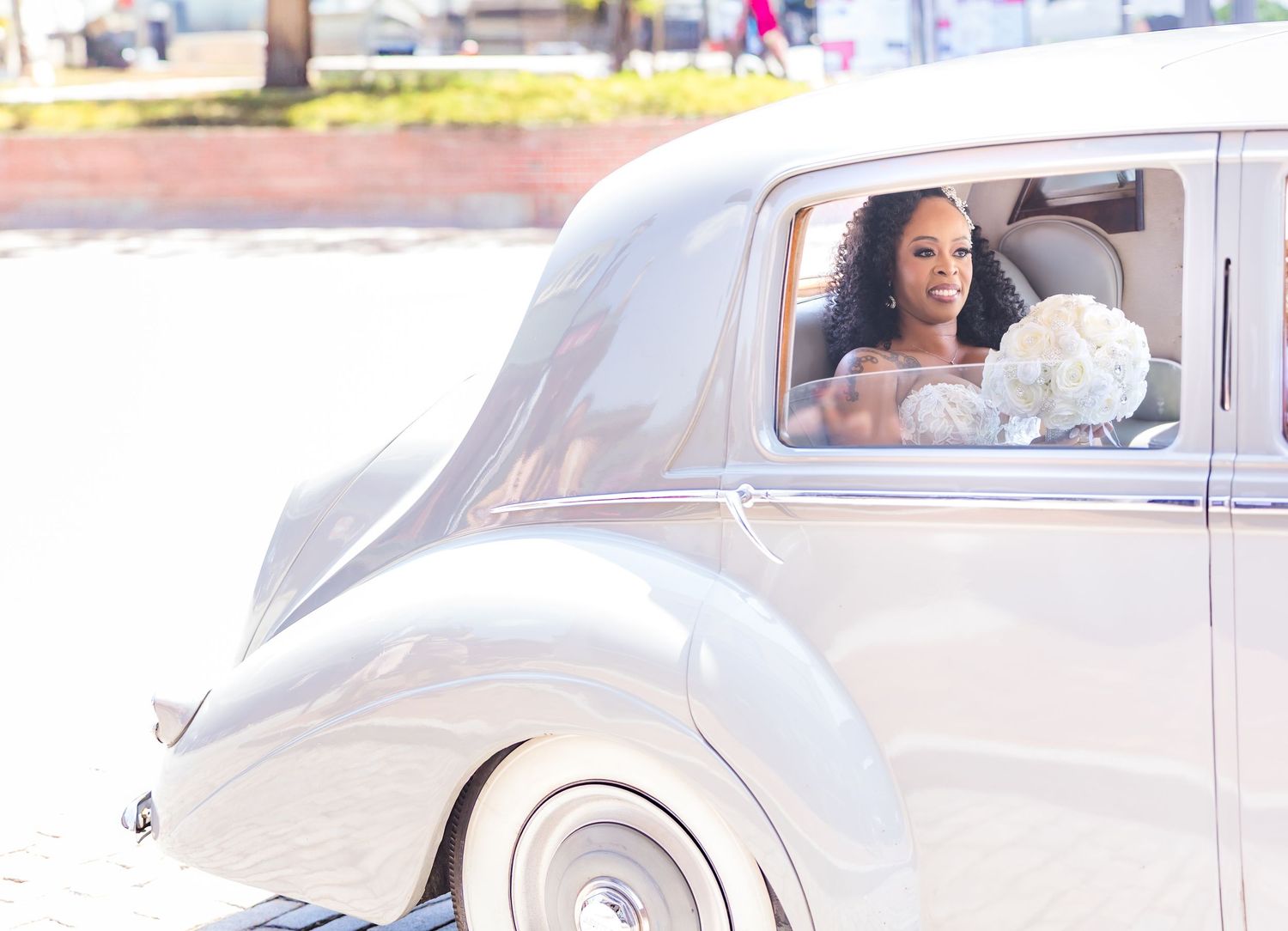 A classic vintage white car parked outside during a wedding celebration.