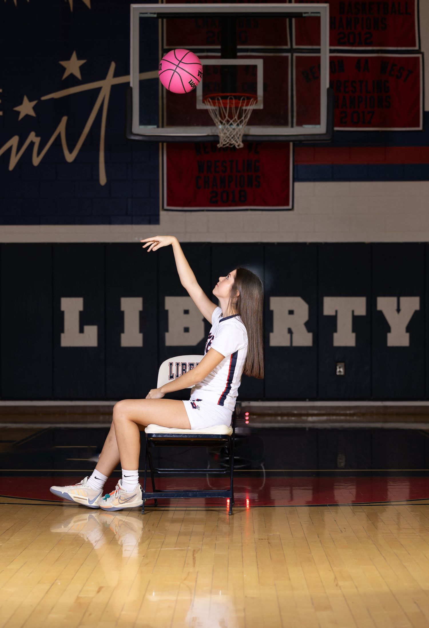 Basketball player practices shooting drills on indoor court with pink ball.