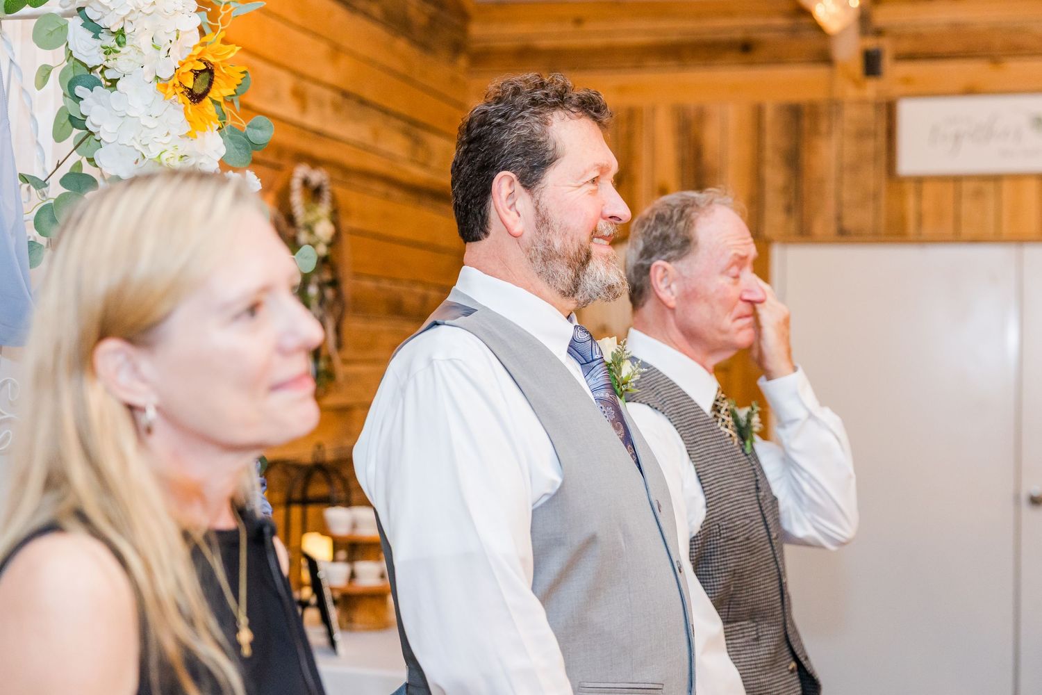 Wedding party members enjoying candid moments in a wooden barn venue.