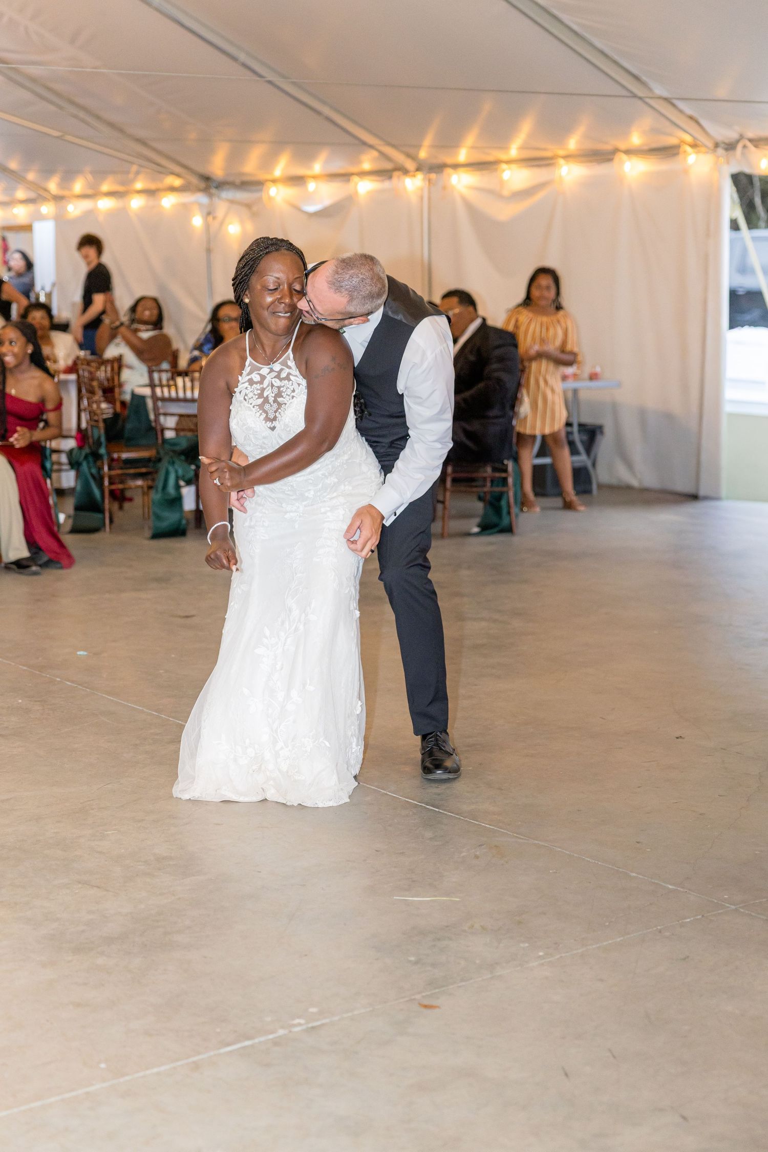 Wedding celebration in a spacious white tent with guests dancing on the dance floor.